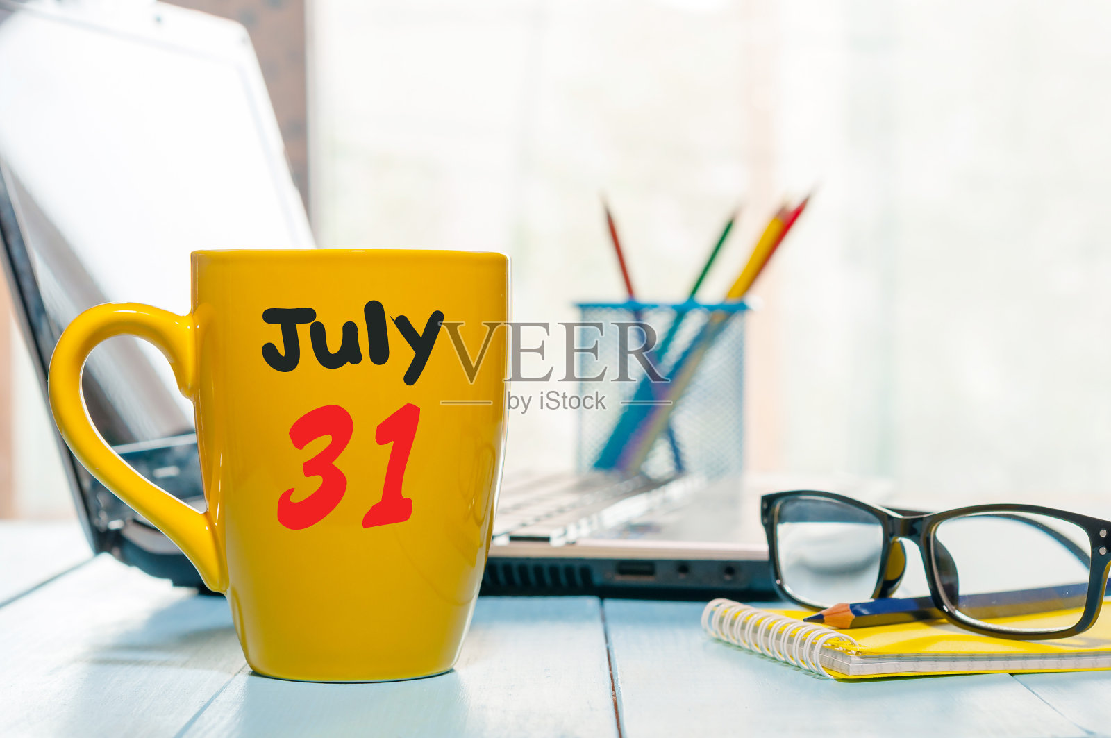 7月31日。月31日，彩色日历上的黄色早上咖啡杯在经理的工作背景。夏天的时间。文本空白照片摄影图片