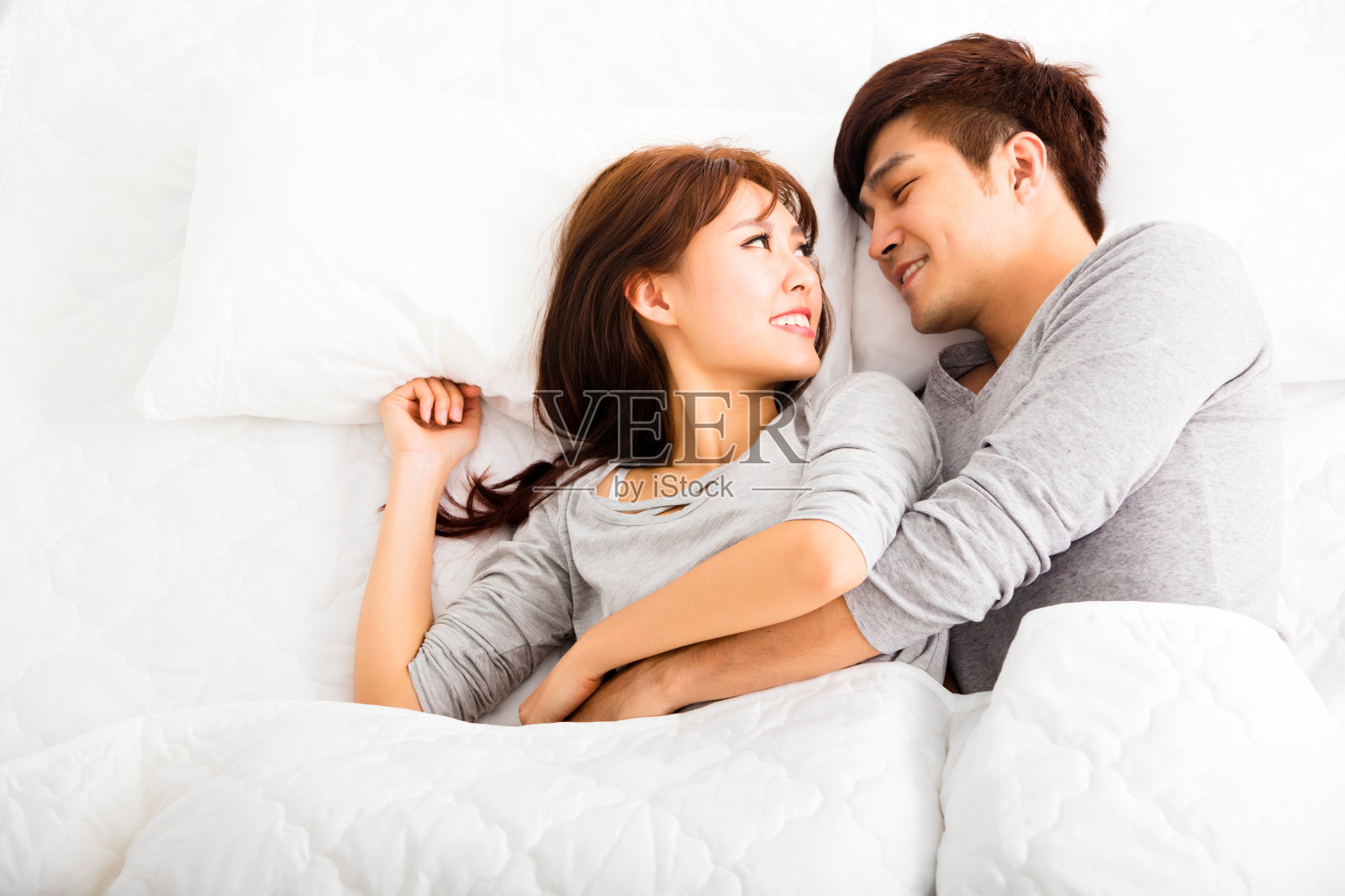 一对幸福可爱的年轻夫妇躺在床上照片摄影图片