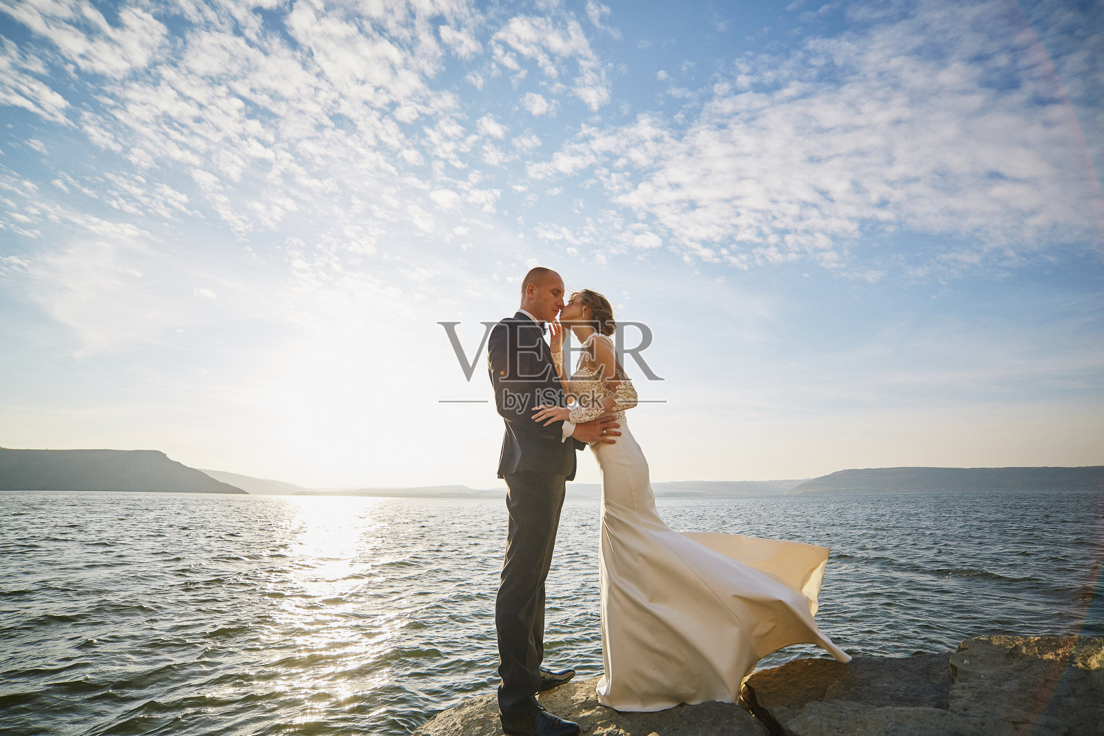情侣们穿着婚纱靠近大海和群山照片摄影图片
