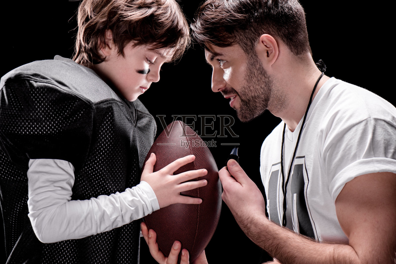 教练和男孩与橄榄球面对面站在黑色的侧视图照片摄影图片