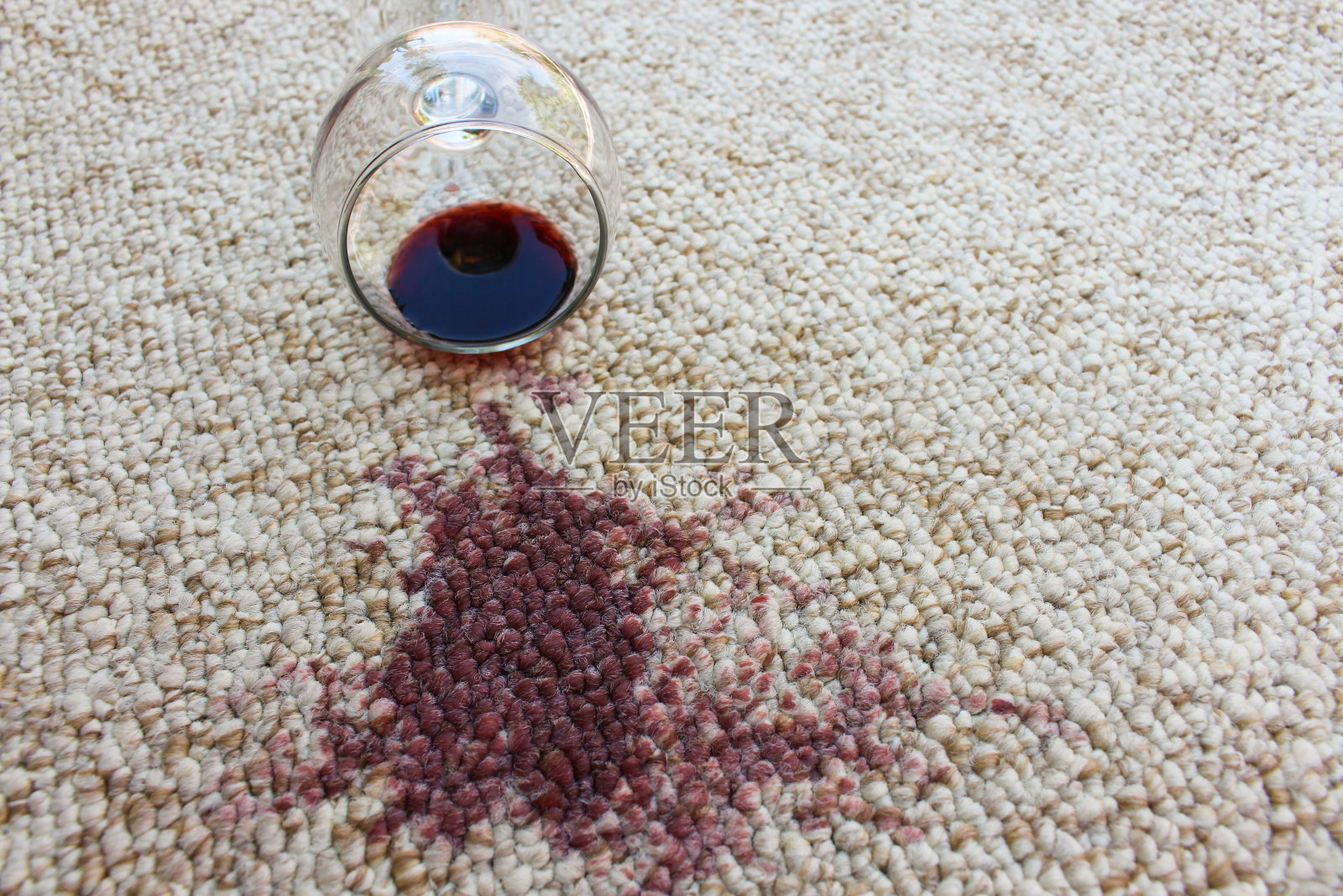 一杯红酒掉在地毯上，酒洒在地毯上照片摄影图片