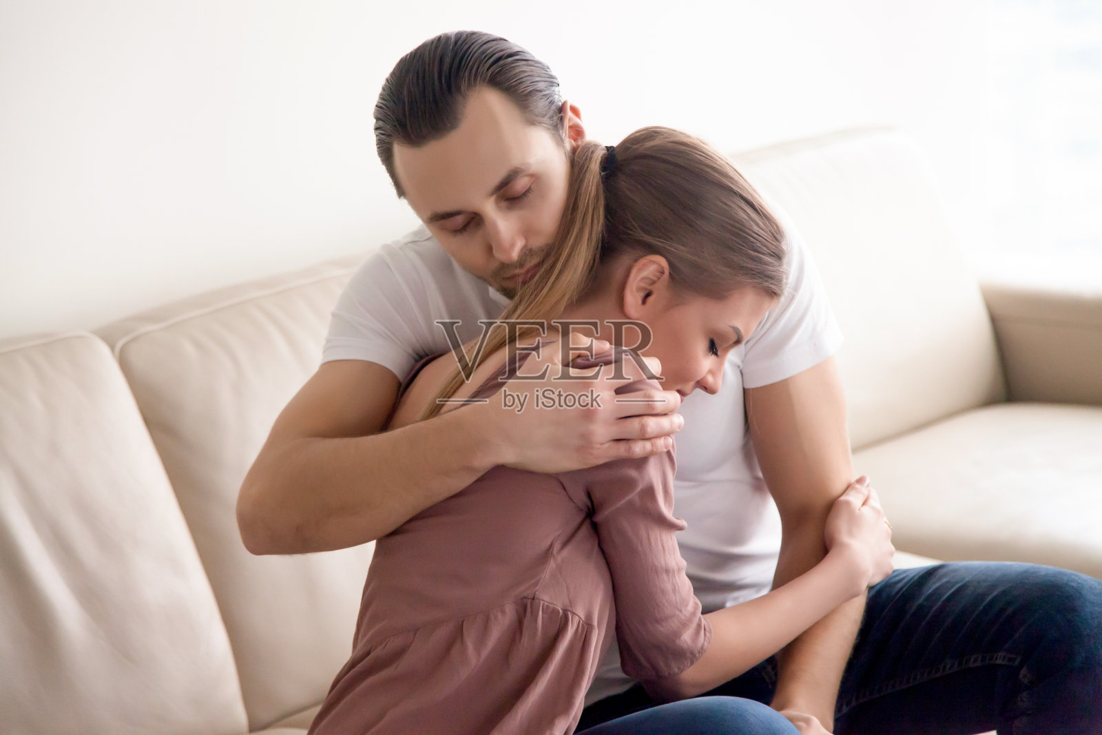 年轻幸福的夫妇坐在室内沙发上拥抱的肖像照片摄影图片