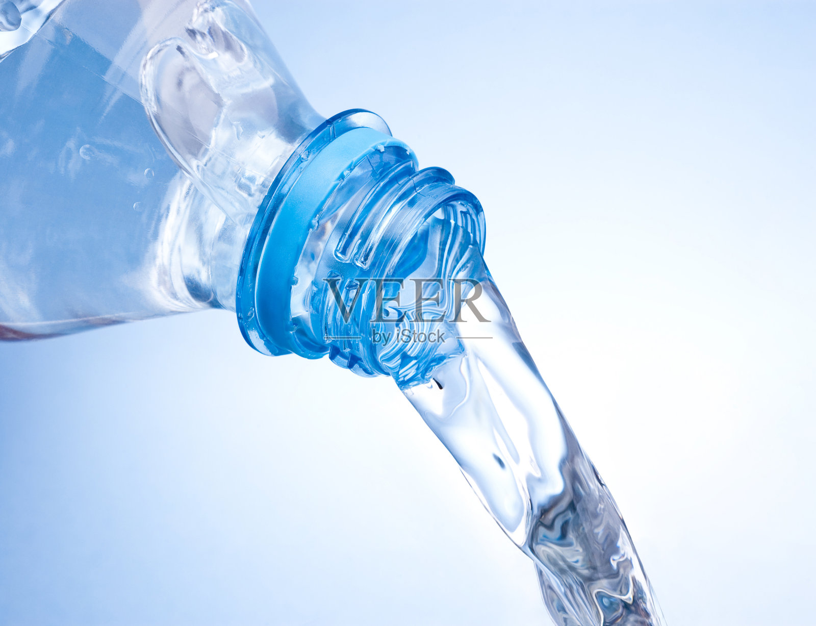 将塑料瓶中的水倒在蓝色背景上照片摄影图片