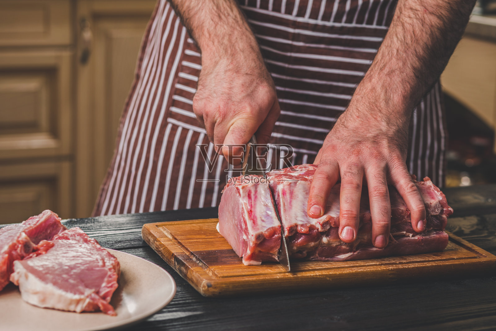 男人在家庭厨房的一块木板上切新鲜的肉照片摄影图片