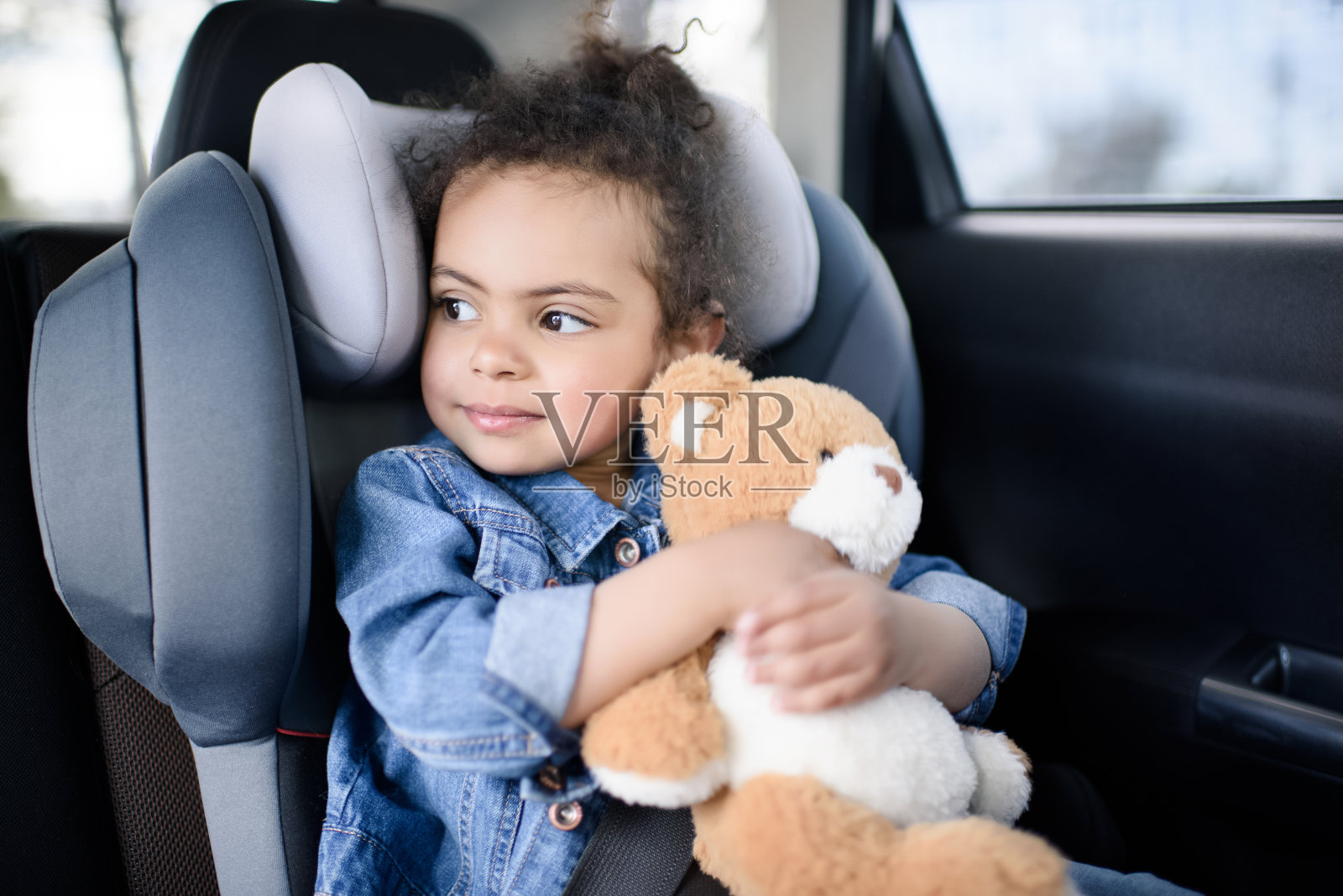 小女孩坐在车里抱着泰迪熊照片摄影图片