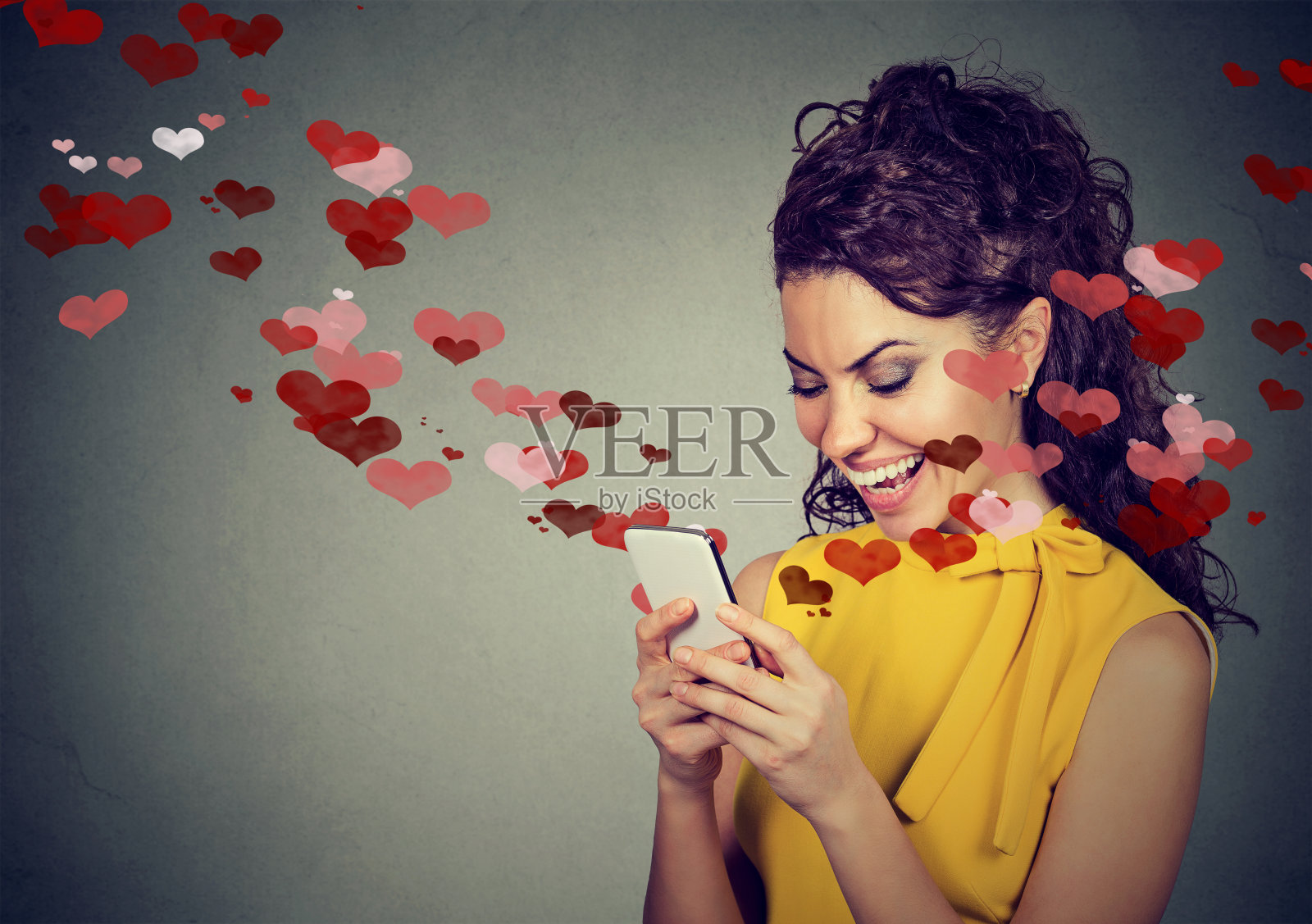 美丽幸福的女人用红心在手机上发爱情短信照片摄影图片