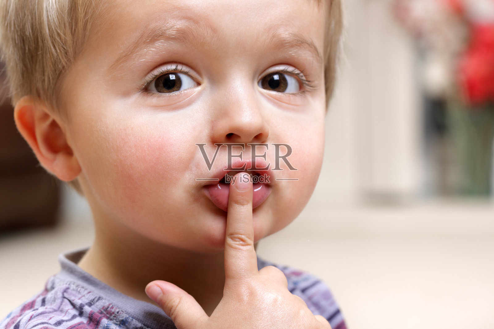 小男孩把手指放在嘴唇上照片摄影图片