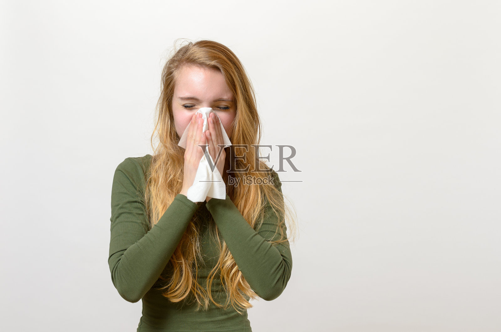 不舒服的年轻女子在擤鼻涕照片摄影图片