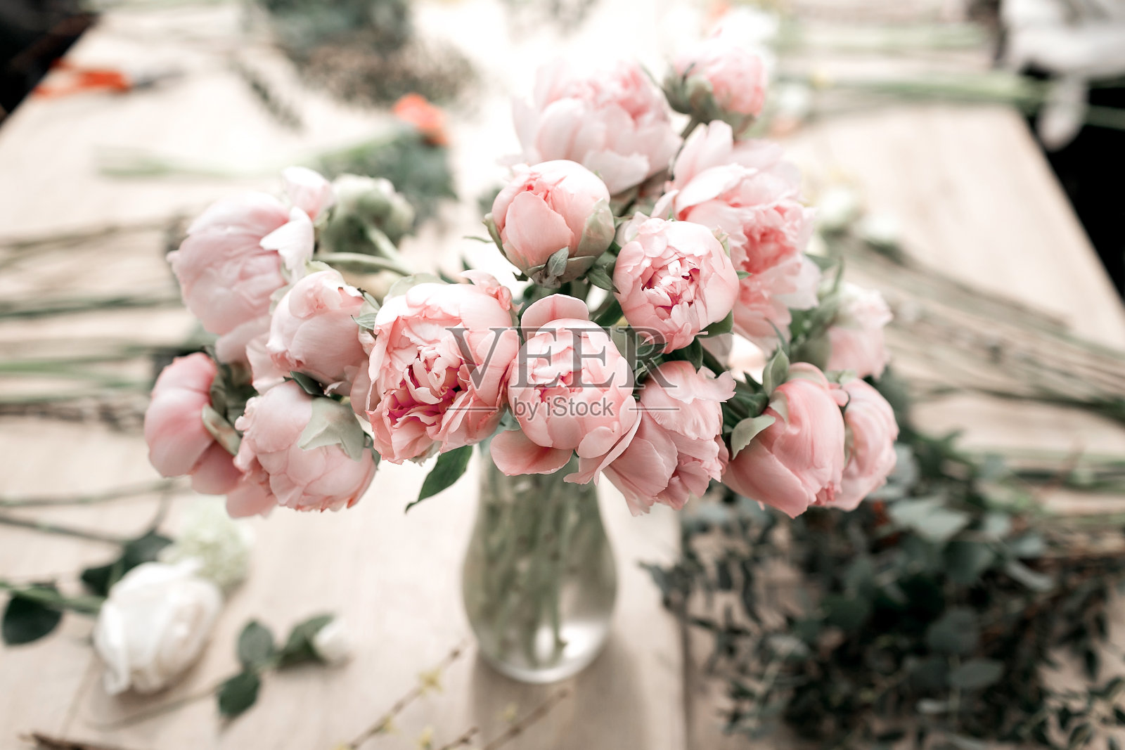 粉红色的牡丹花瓶在木地板和散景背景-复古风格的照片。软的焦点。照片摄影图片