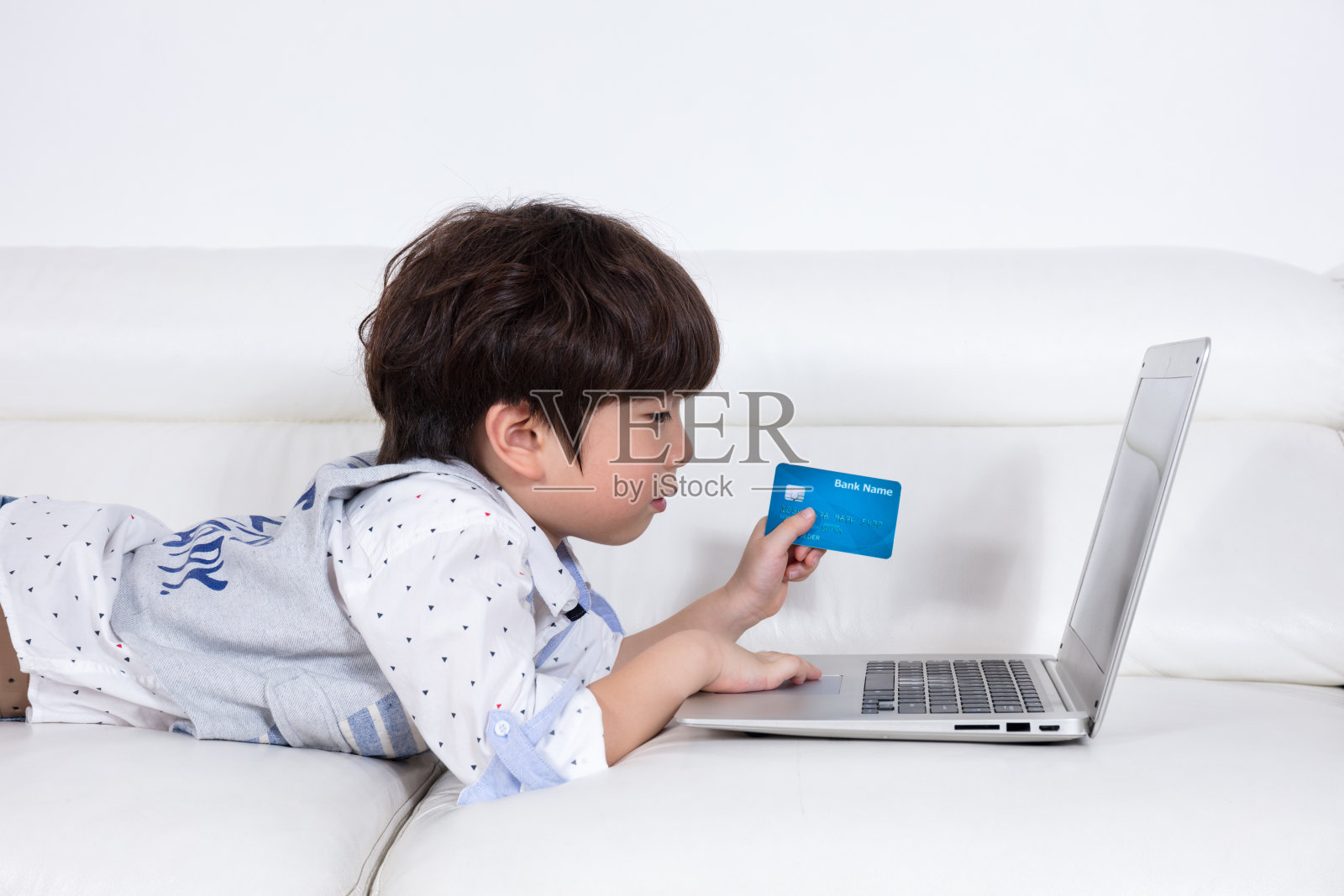 亚洲华人小男孩用信用卡购买笔记本电脑照片摄影图片