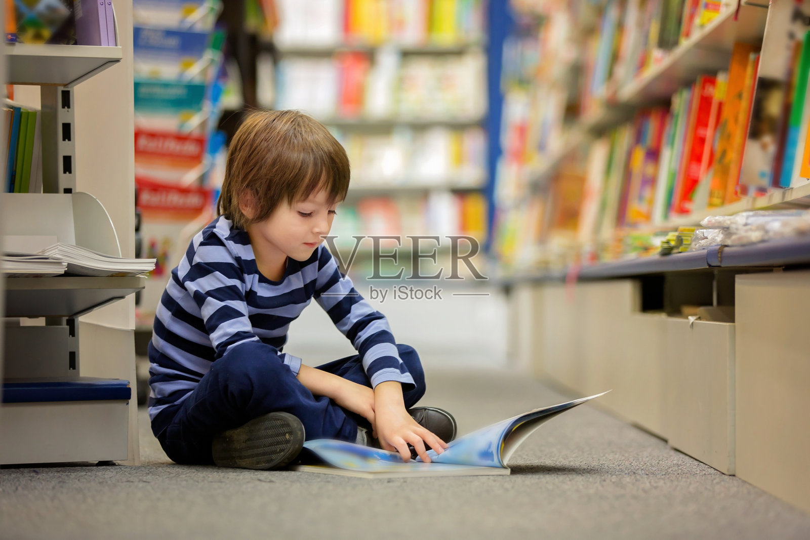 可爱的小男孩，坐在书店里看书照片摄影图片
