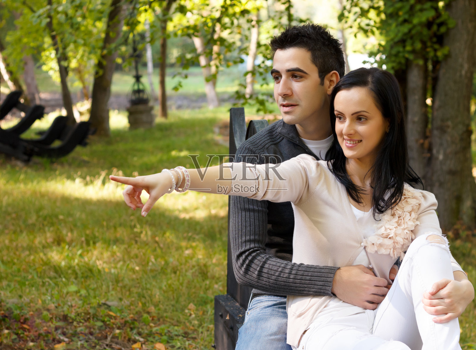 微笑的年轻夫妇坐在公园的长椅上照片摄影图片