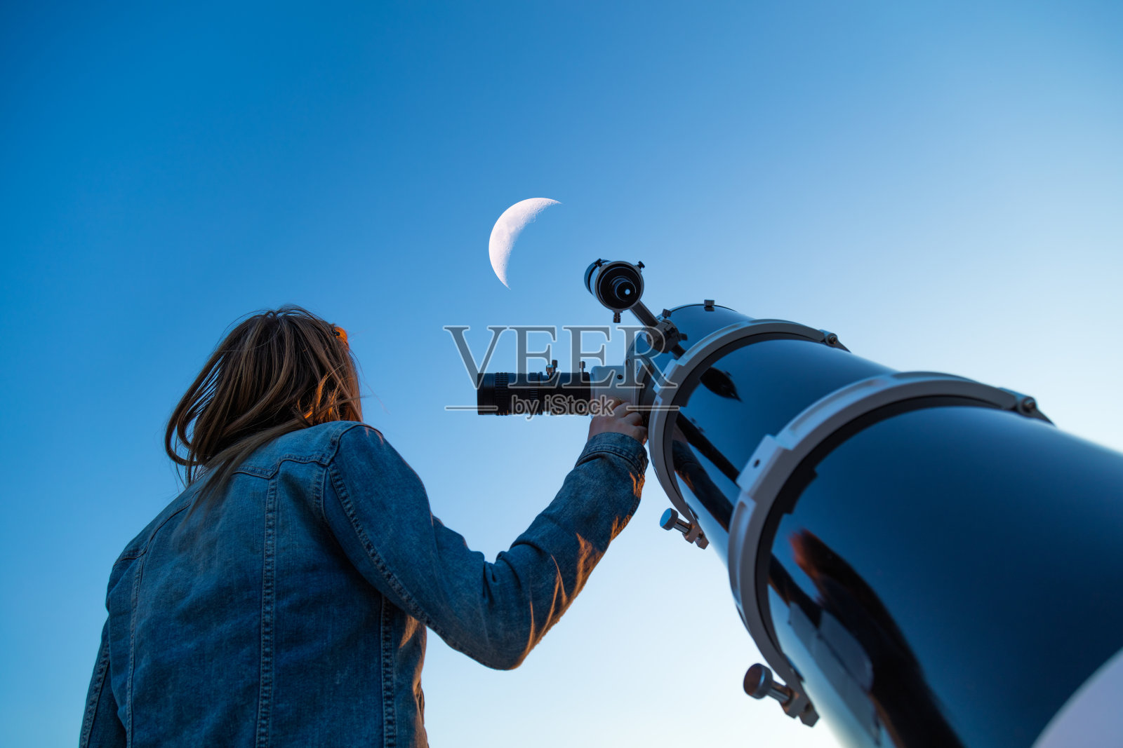 用望远镜看月亮的女孩。照片摄影图片