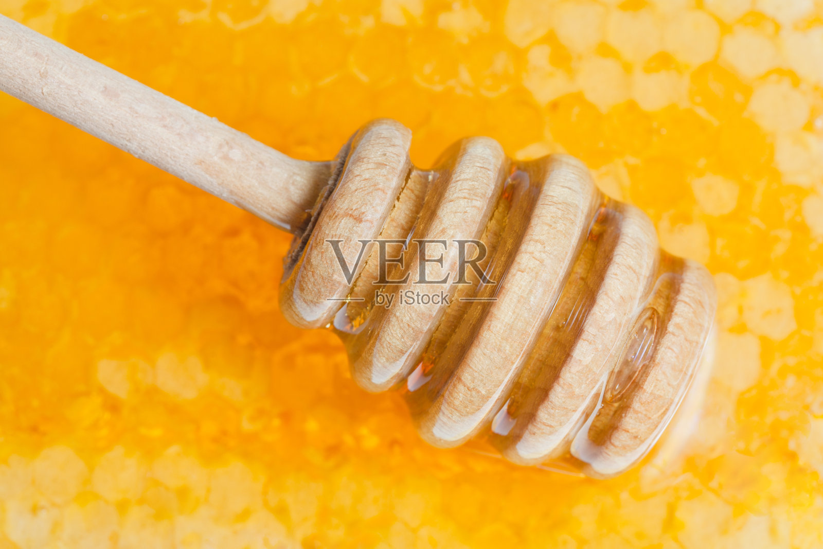木质蜂蜜粘在新鲜蜂蜜表面照片摄影图片