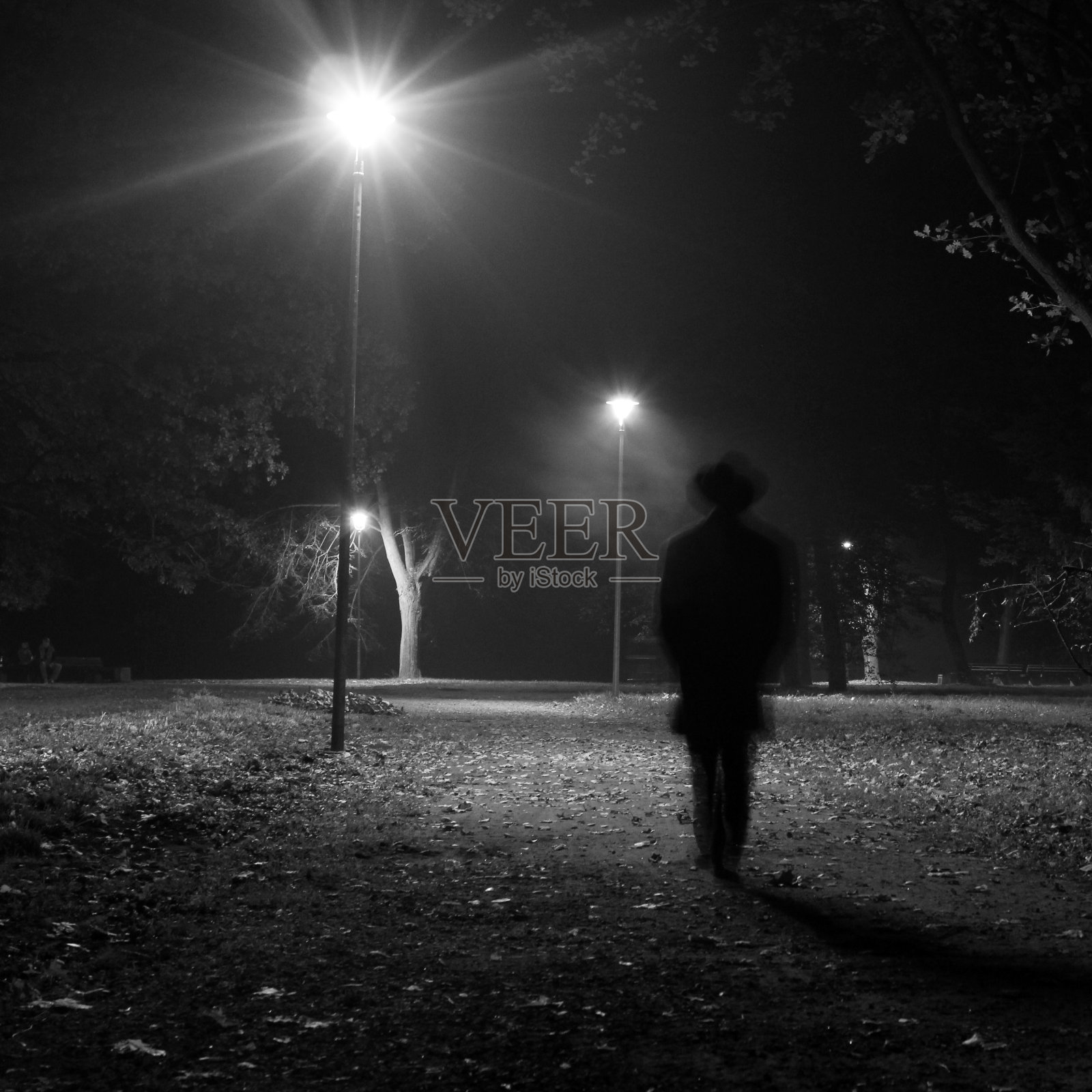 一个超现实的男人晚上在公园里散步。照片摄影图片
