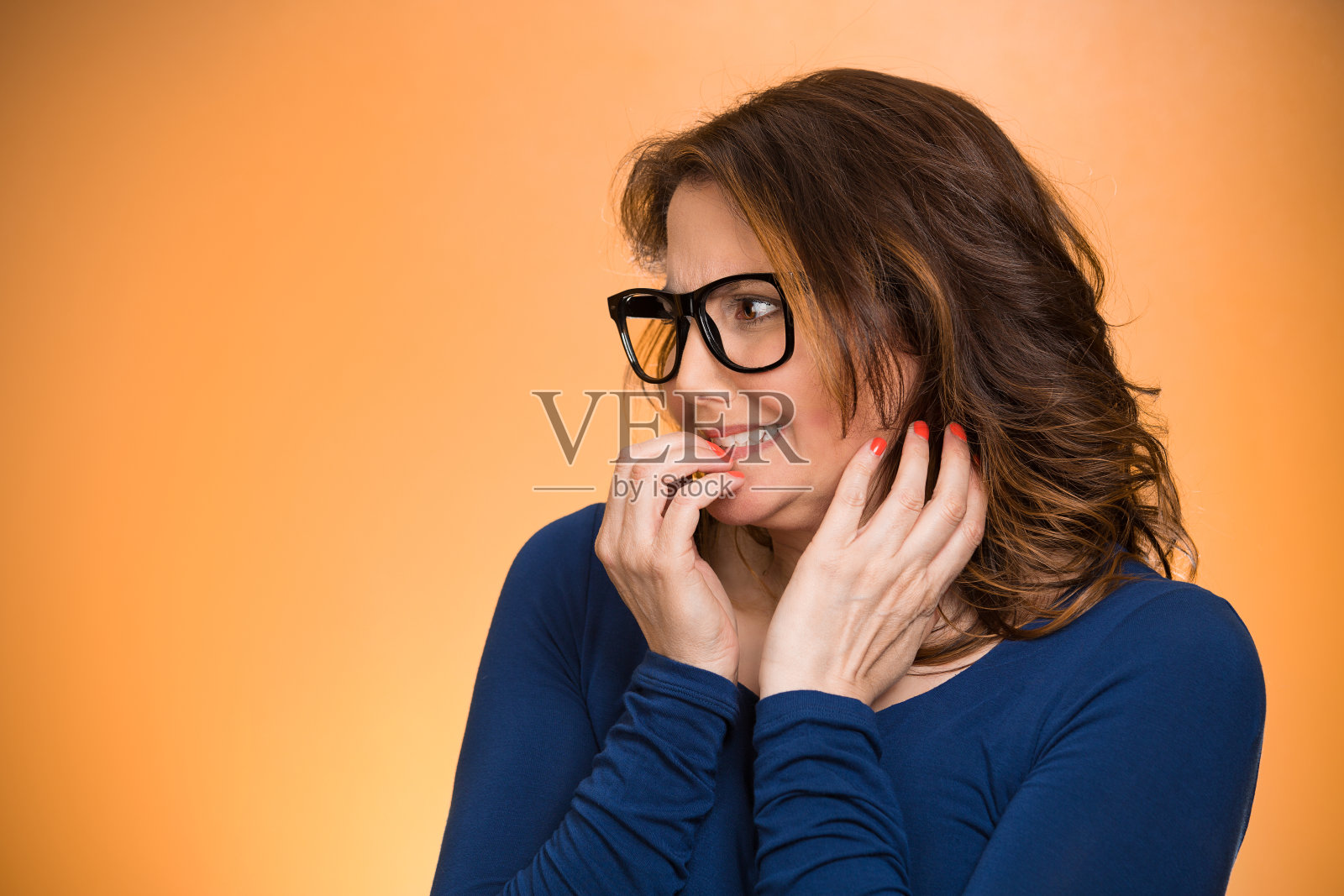 特写肖像神经质的女人戴着眼镜咬她的指甲渴望的东西，照片摄影图片