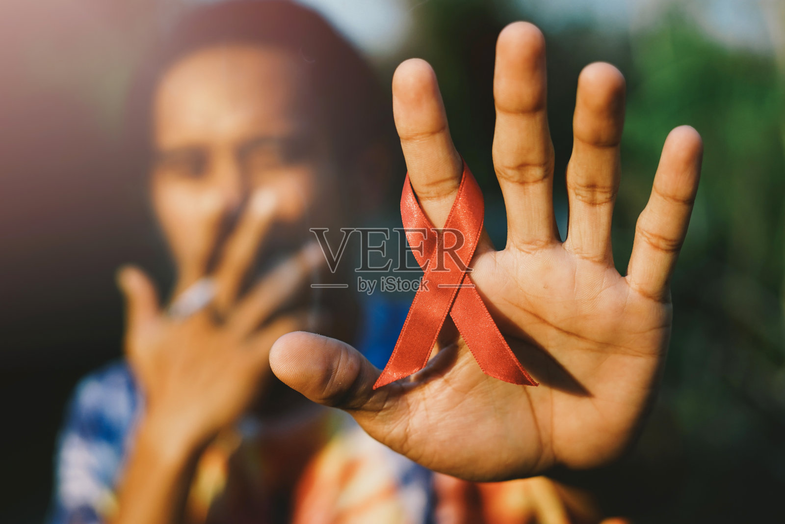 手里拿着红色的艾滋病丝带。照片摄影图片