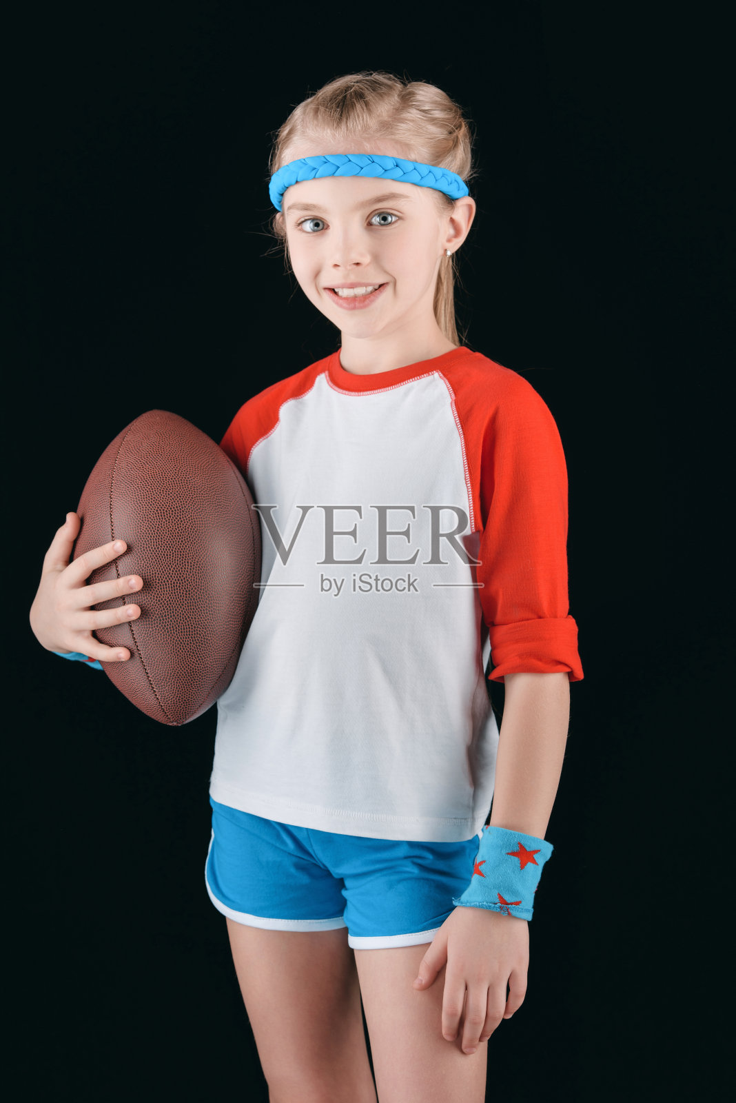 肖像的小运动女孩与橄榄球孤立的黑色，体育儿童的概念照片摄影图片
