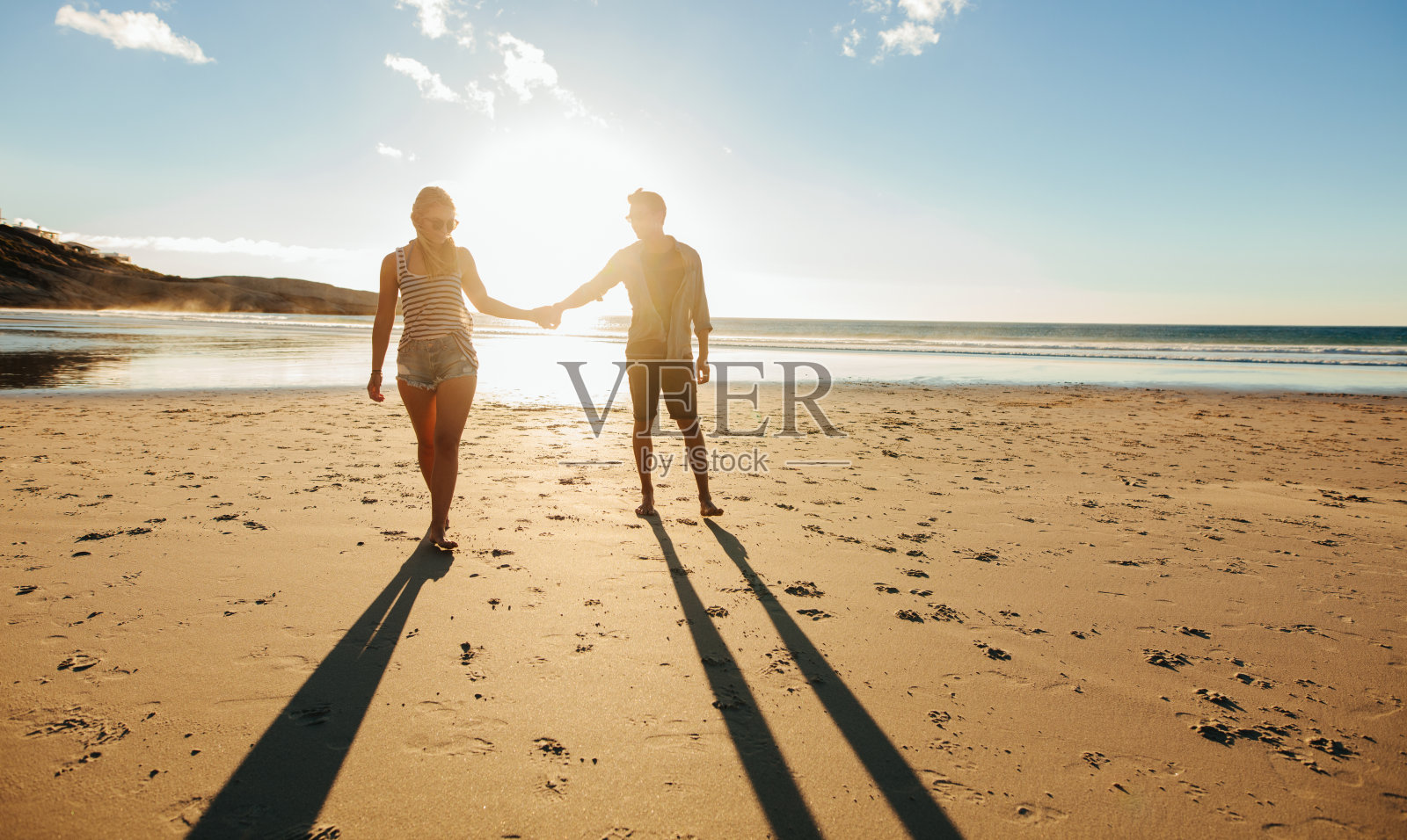 一对情侣在日落时分一起在海滩上散步照片摄影图片