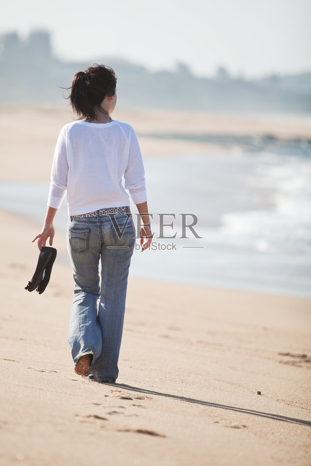 一位年轻的女士在海滩上散步照片摄影图片