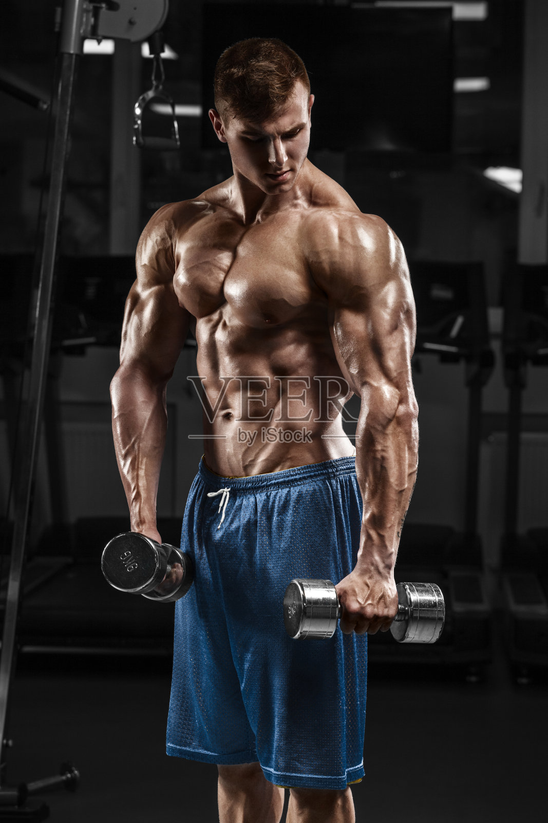 肌肉男在健身房锻炼用杠铃，强壮的男性赤裸上身腹肌照片摄影图片