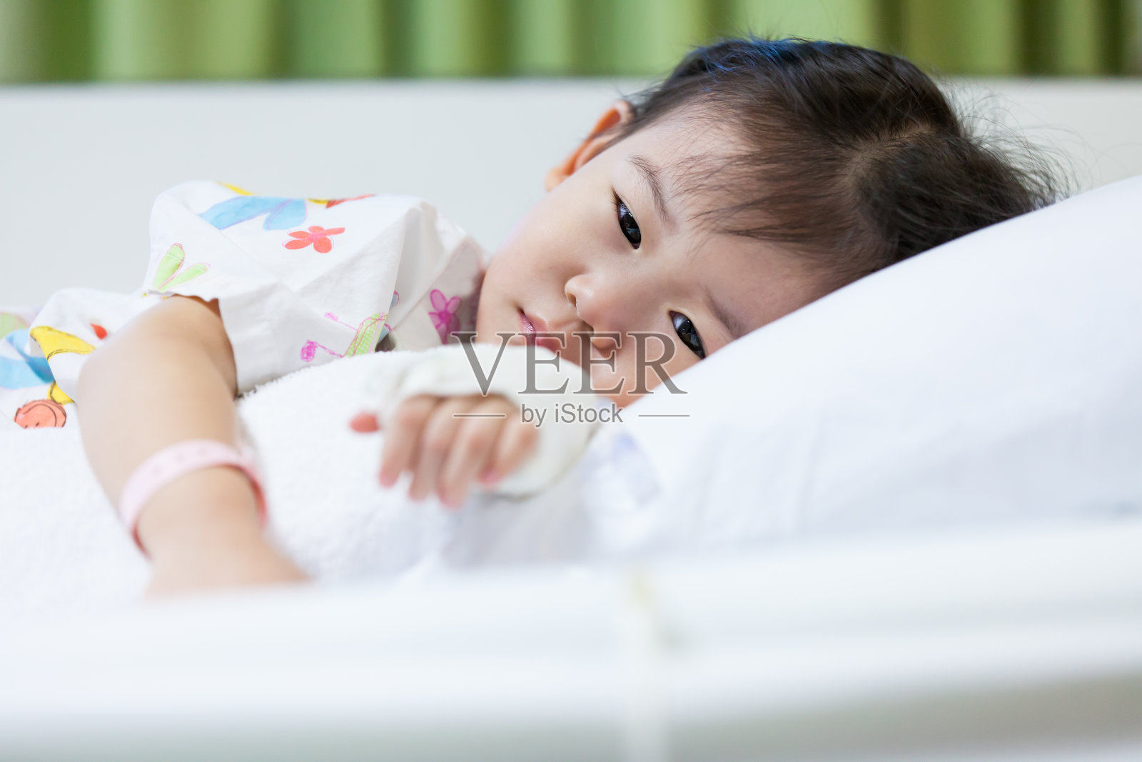 生病的孩子住院了，手上的女孩静脉注射生理盐水。照片摄影图片