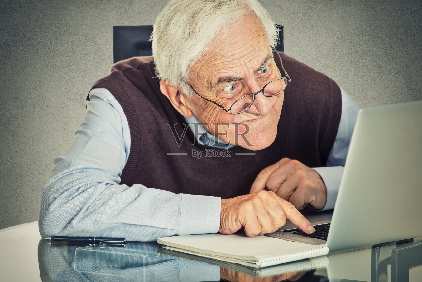 一位老人坐在桌子旁使用电脑照片摄影图片