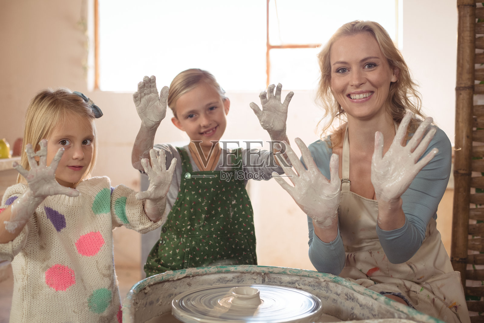 妇女和女孩在陶器店举手照片摄影图片