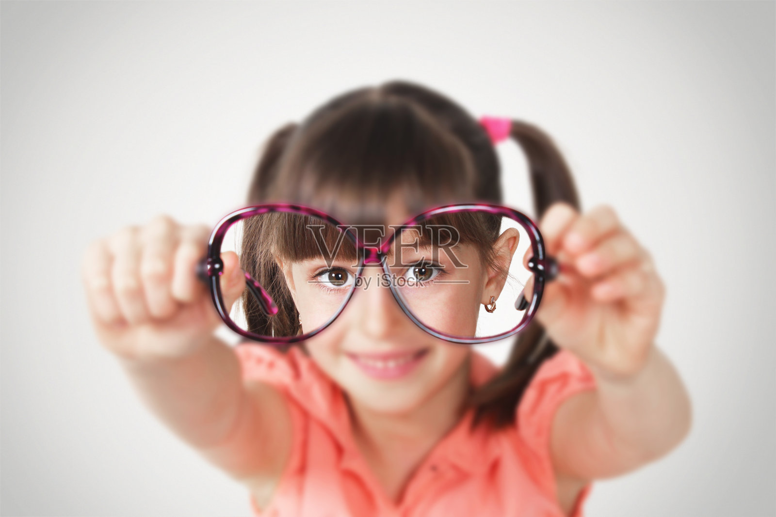 小女孩拿着眼镜，健康视力理念。软焦点照片摄影图片