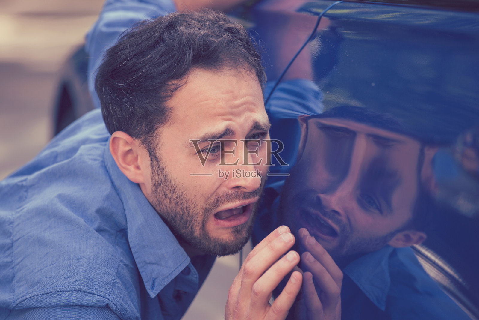 沮丧沮丧的年轻人看划痕和凹痕在他的汽车户外照片摄影图片