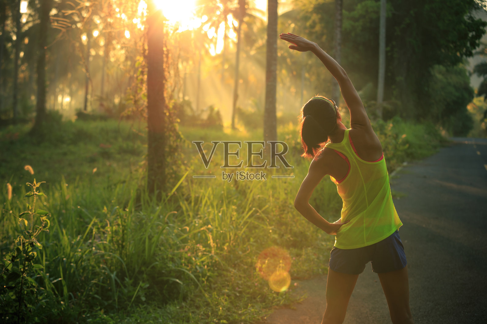 年轻的女性跑步者在晨跑前热身森林小径照片摄影图片
