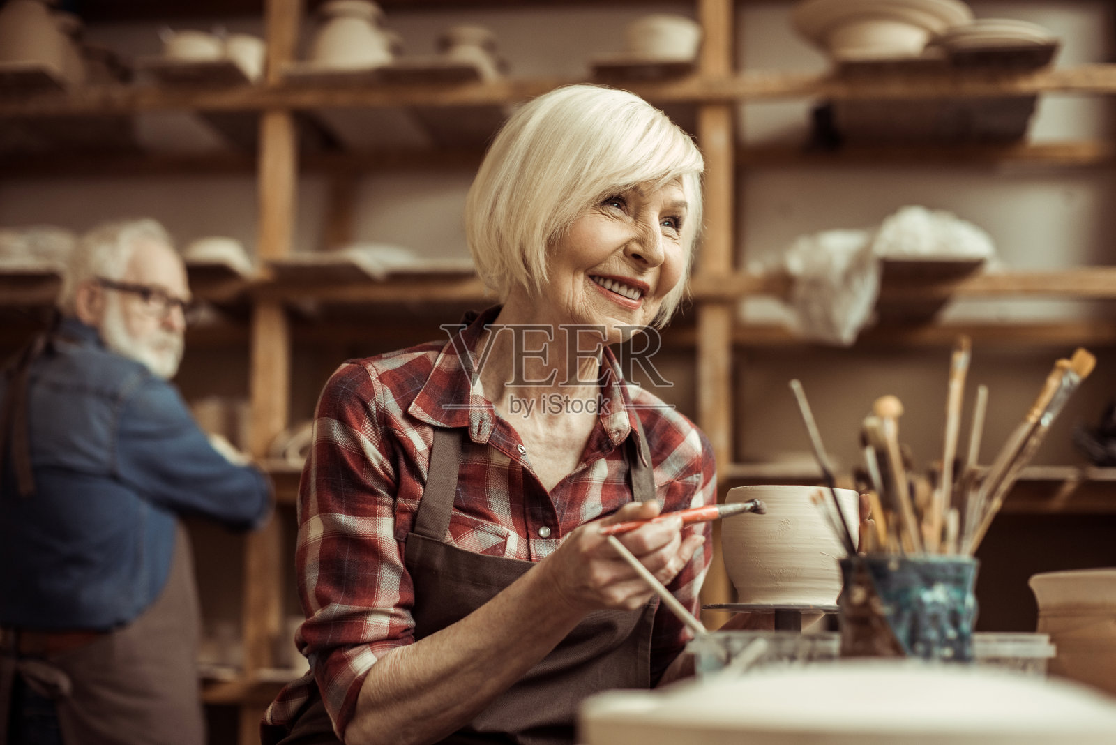 和高级陶工在车间画陶罐的女人照片摄影图片