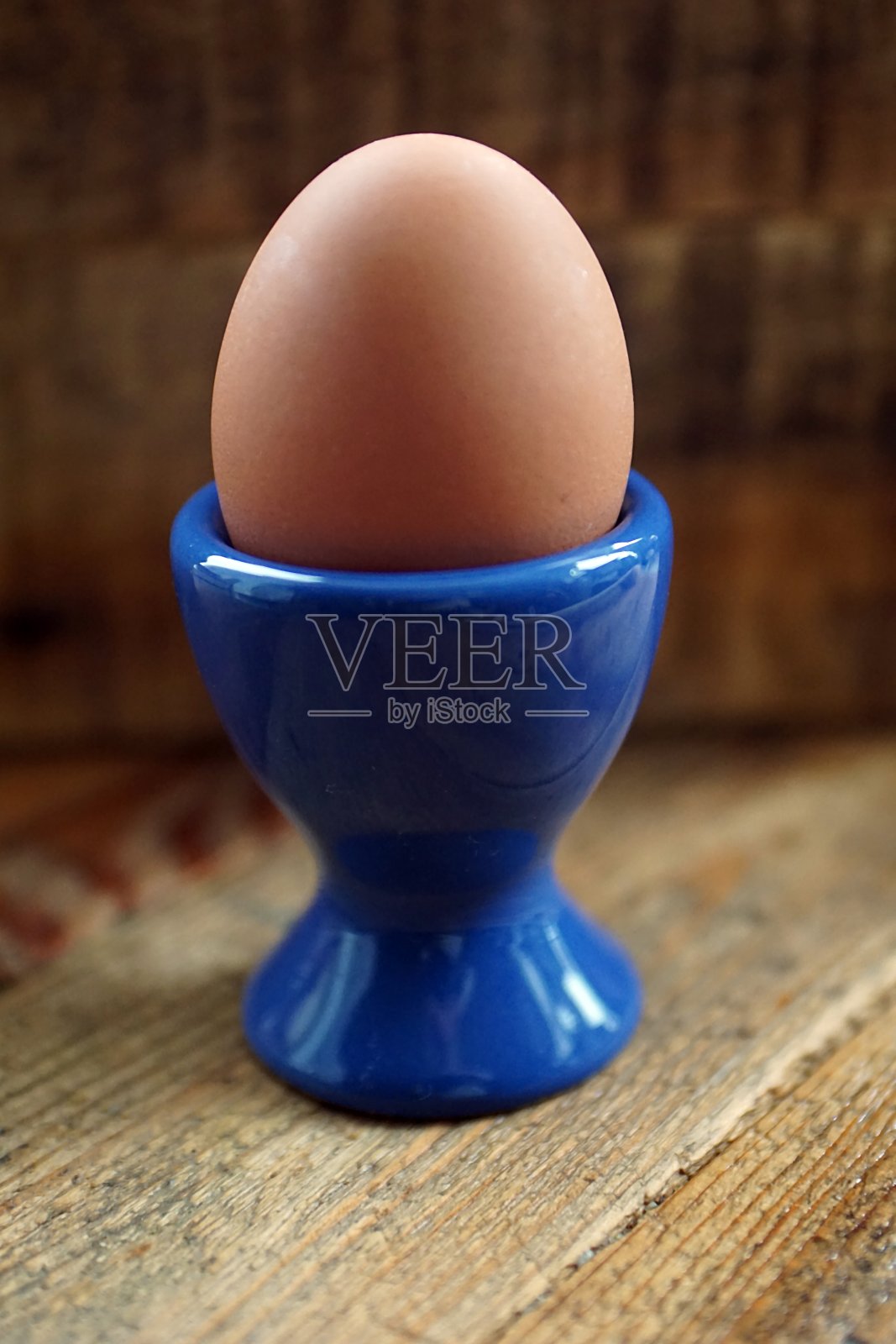 鸡蛋在一个蓝色的蛋杯木制背景照片摄影图片