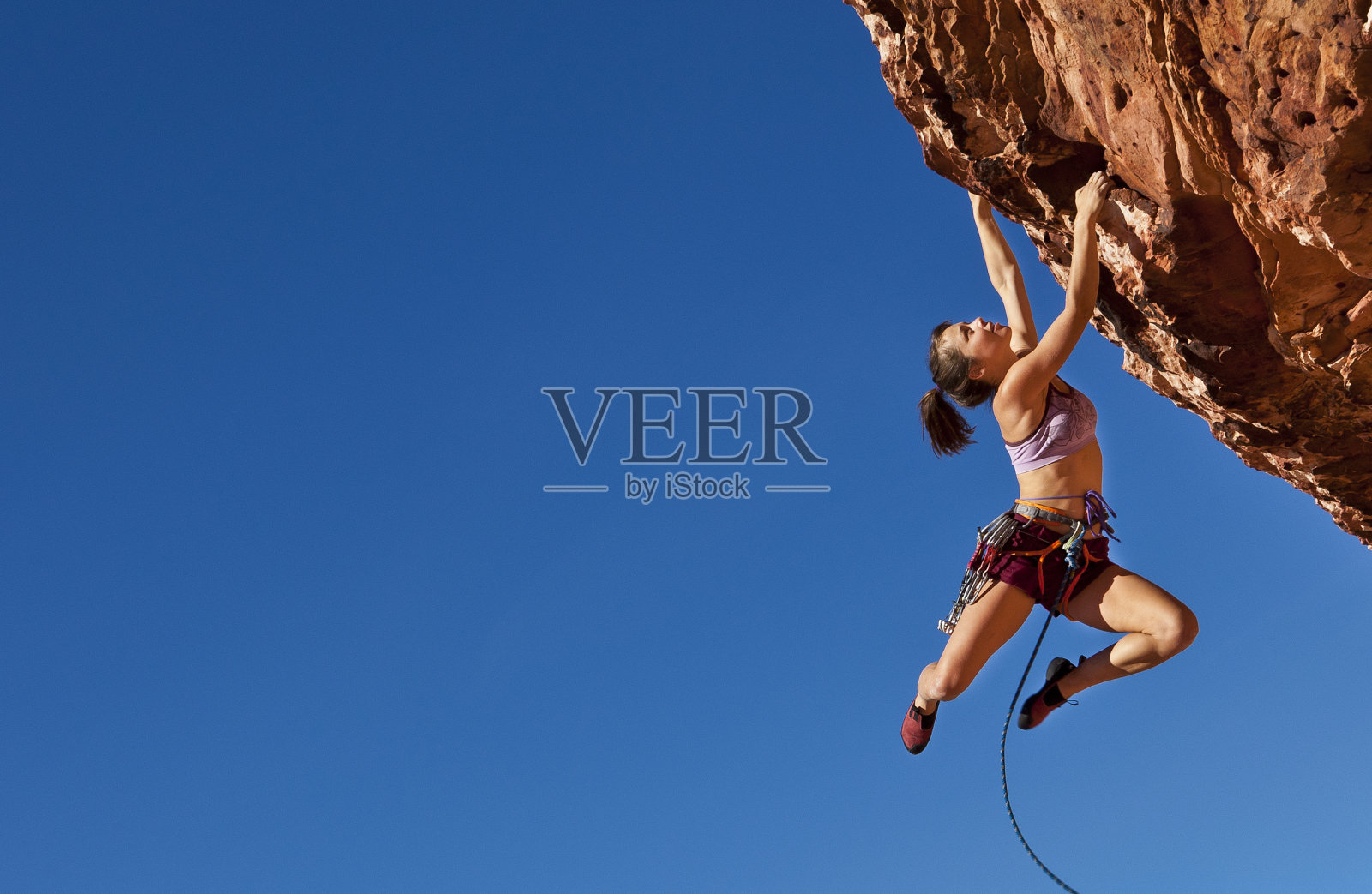女性攀登者紧紧抓住悬崖。照片摄影图片