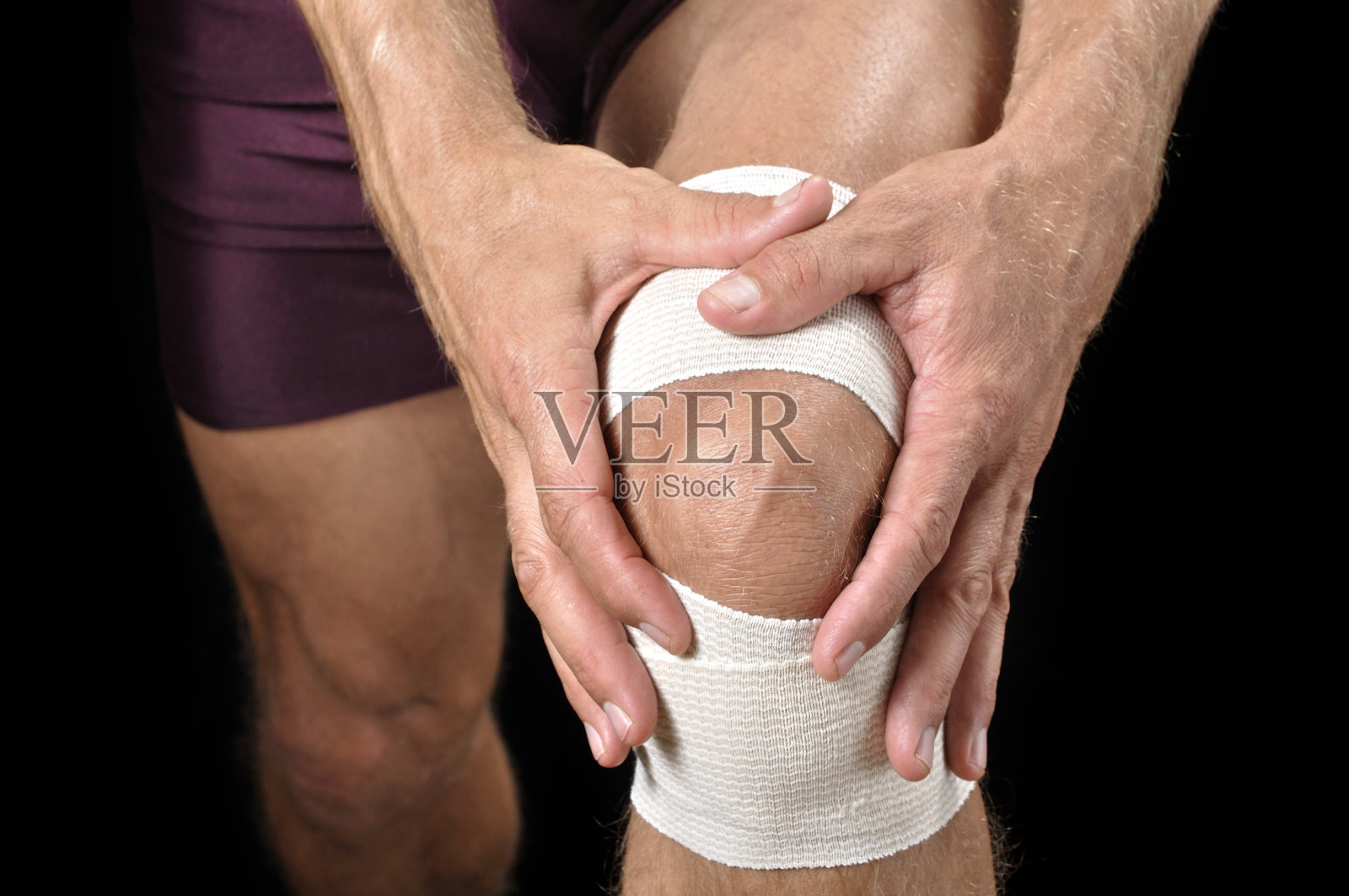 运动员触碰包扎好的膝盖伤照片摄影图片