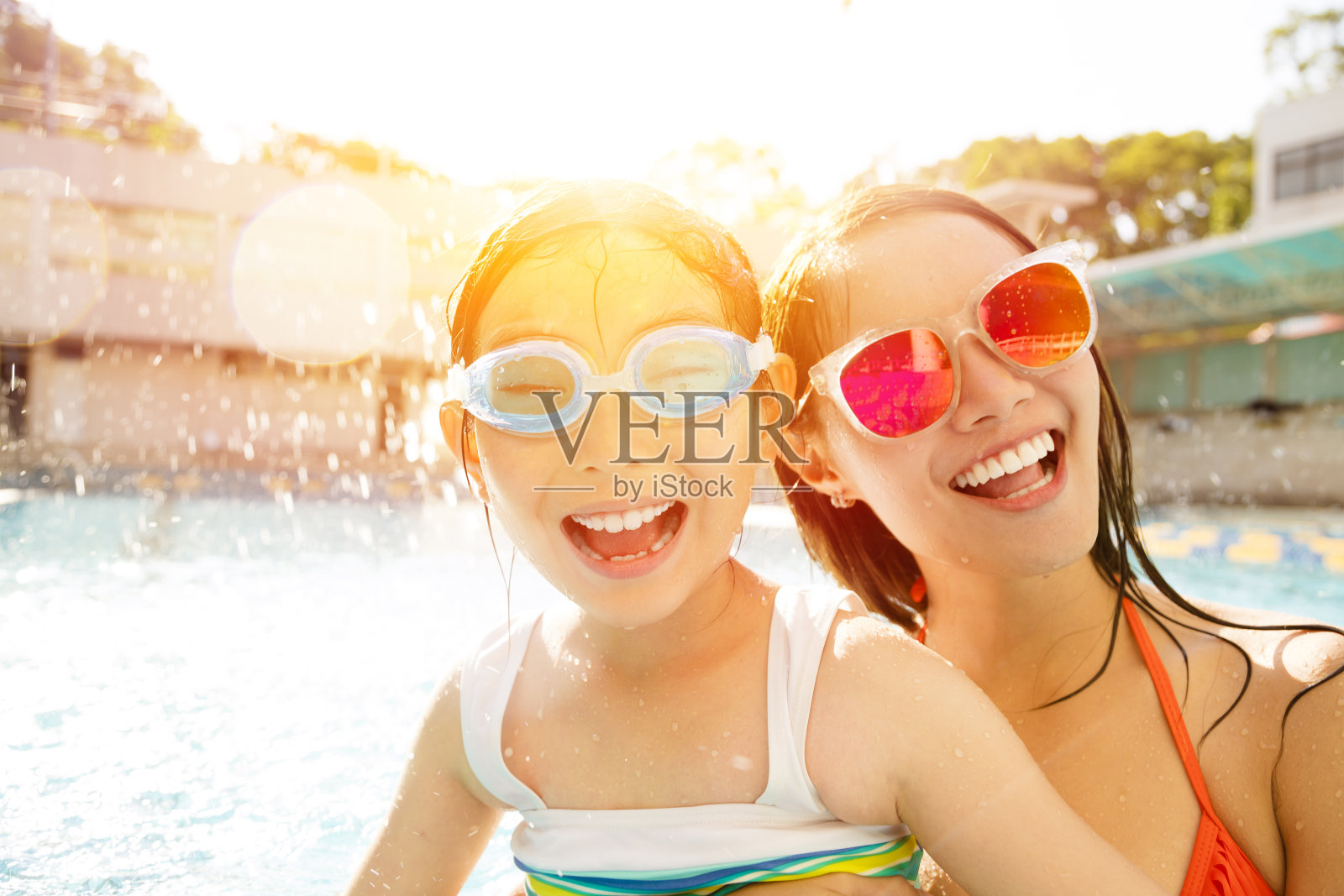 快乐的妈妈和女儿在游泳池里玩照片摄影图片