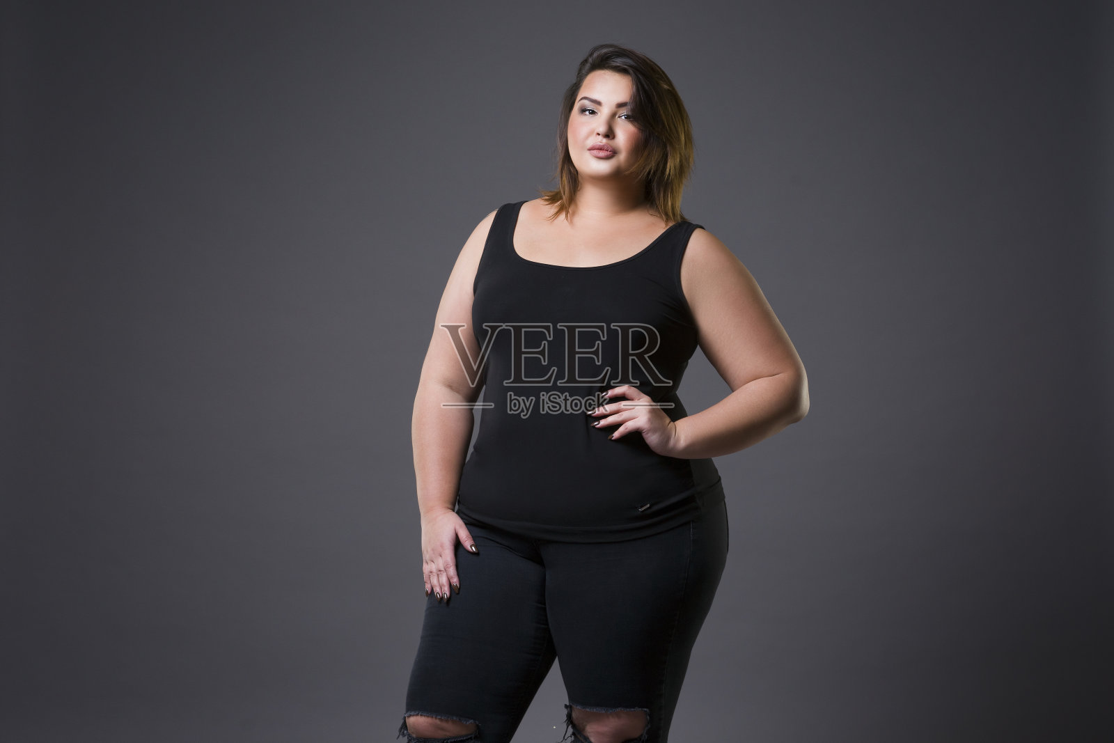 加码时装模特在休闲服装，肥胖的女人在灰色的背景，超重的女性身体照片摄影图片