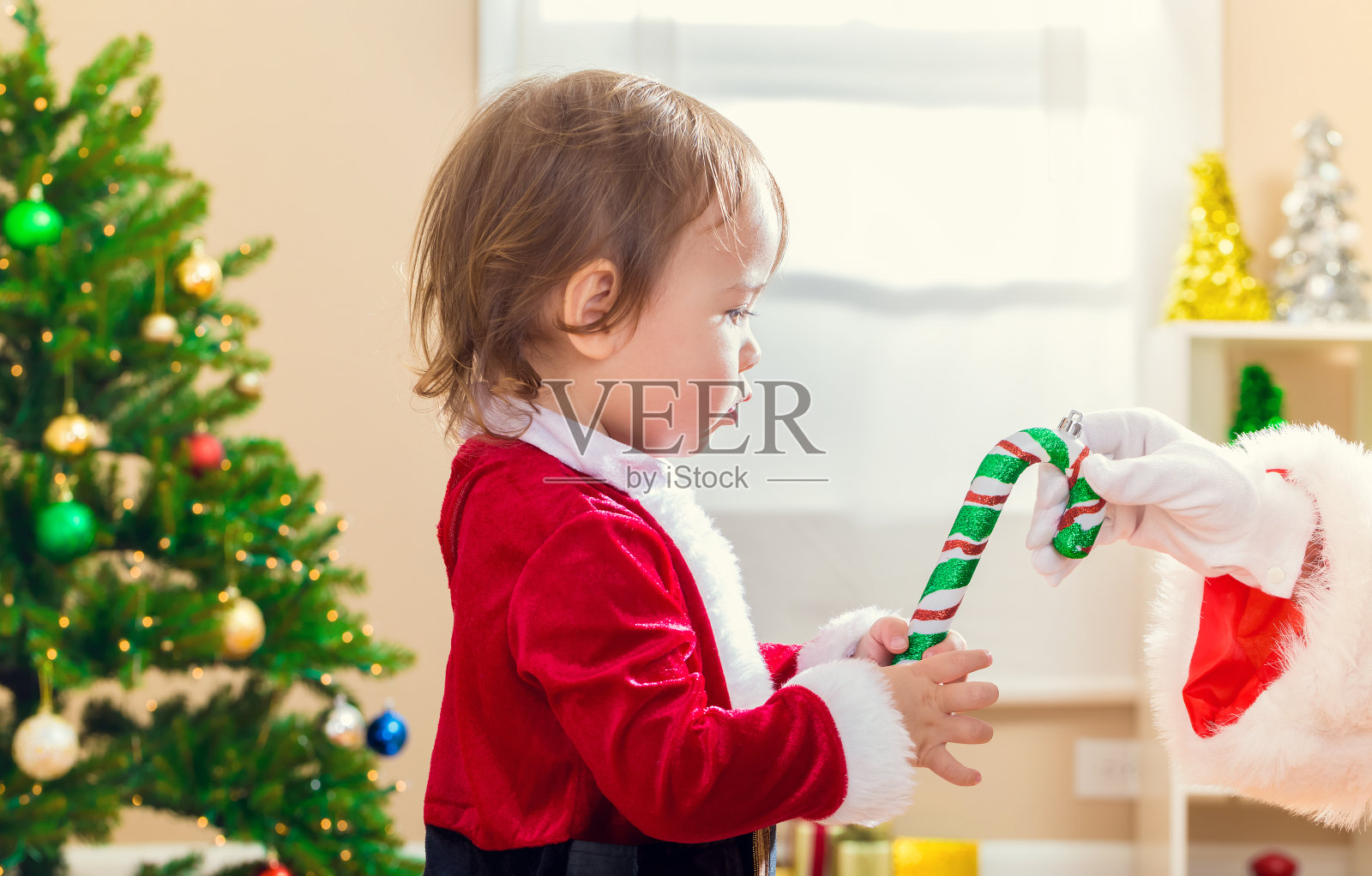 一个蹒跚学步的小女孩收到了圣诞老人送的拐杖糖照片摄影图片