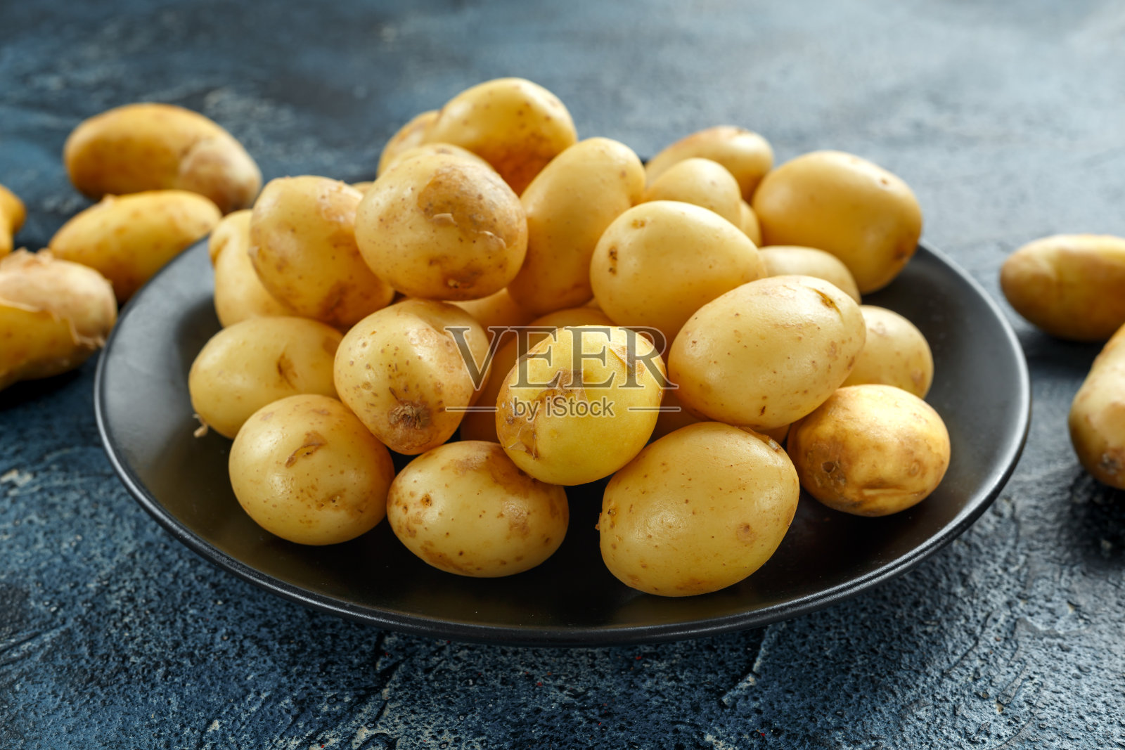 黑色盘子里的新生生土豆照片摄影图片