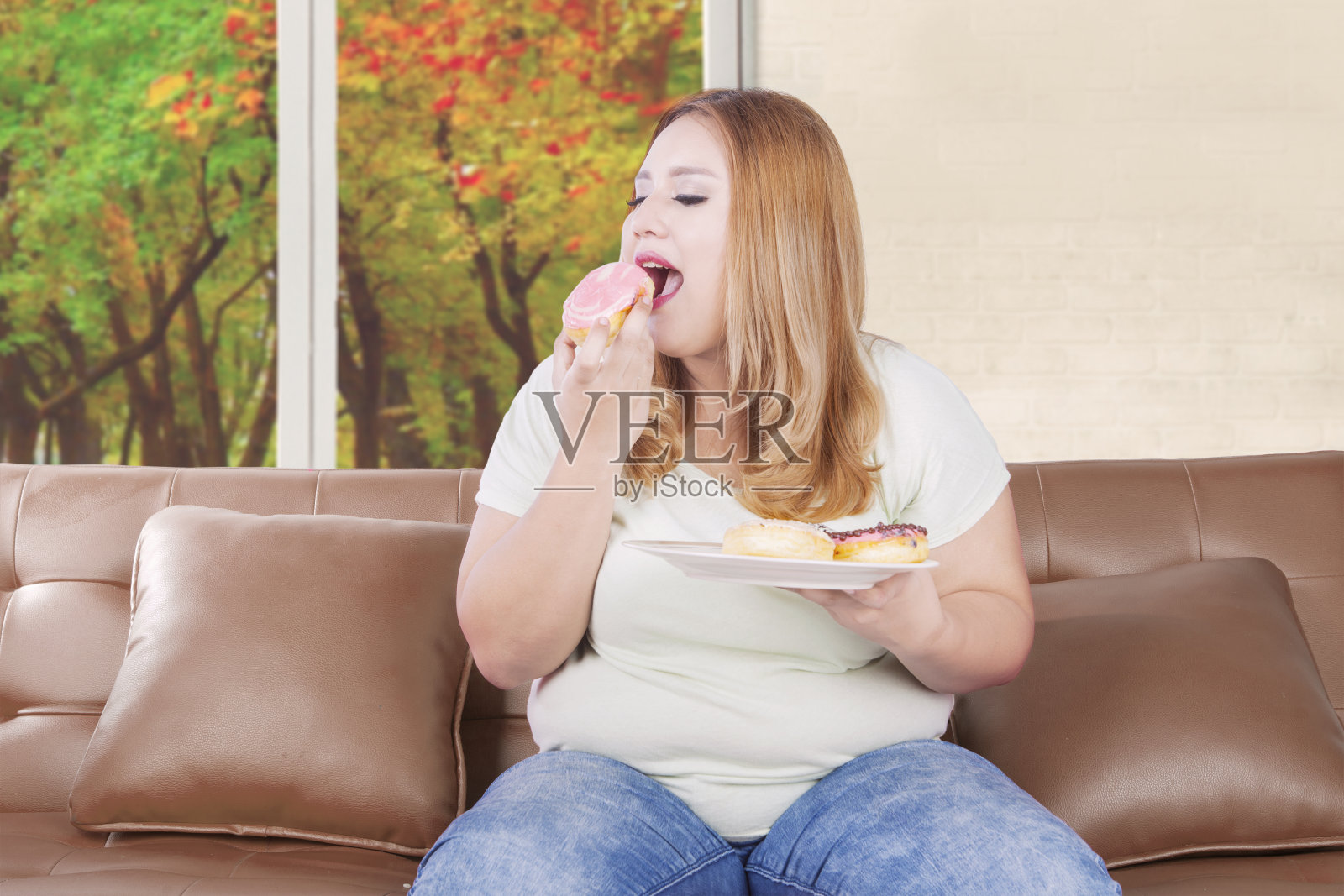 饥饿的金发女人吃甜甜圈照片摄影图片