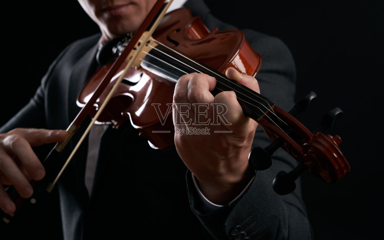 小提琴手的手。在音符背景下演奏小提琴的音乐家、演奏家、小提琴家。照片摄影图片