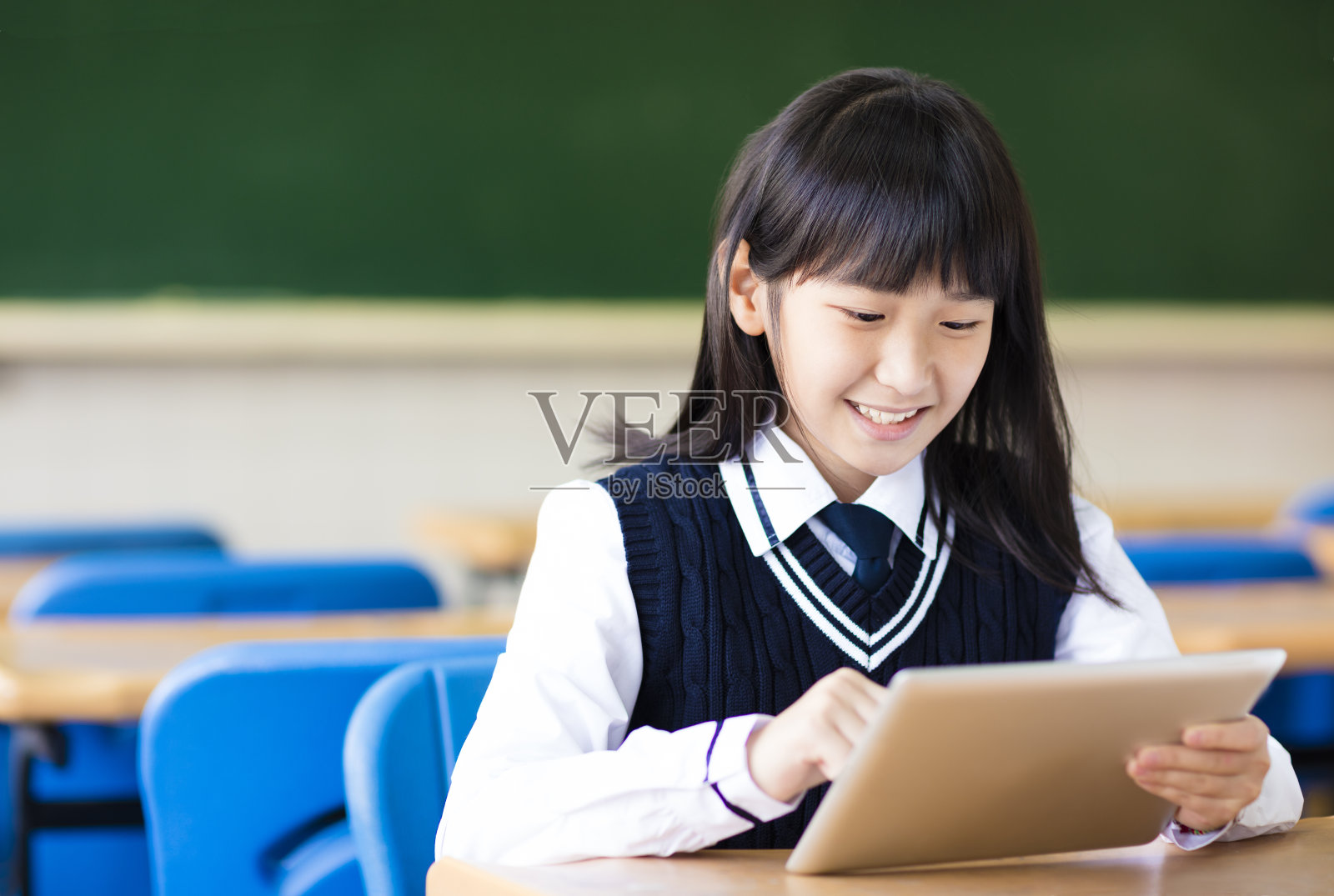 快乐漂亮的学生女孩与平板电脑在教室照片摄影图片
