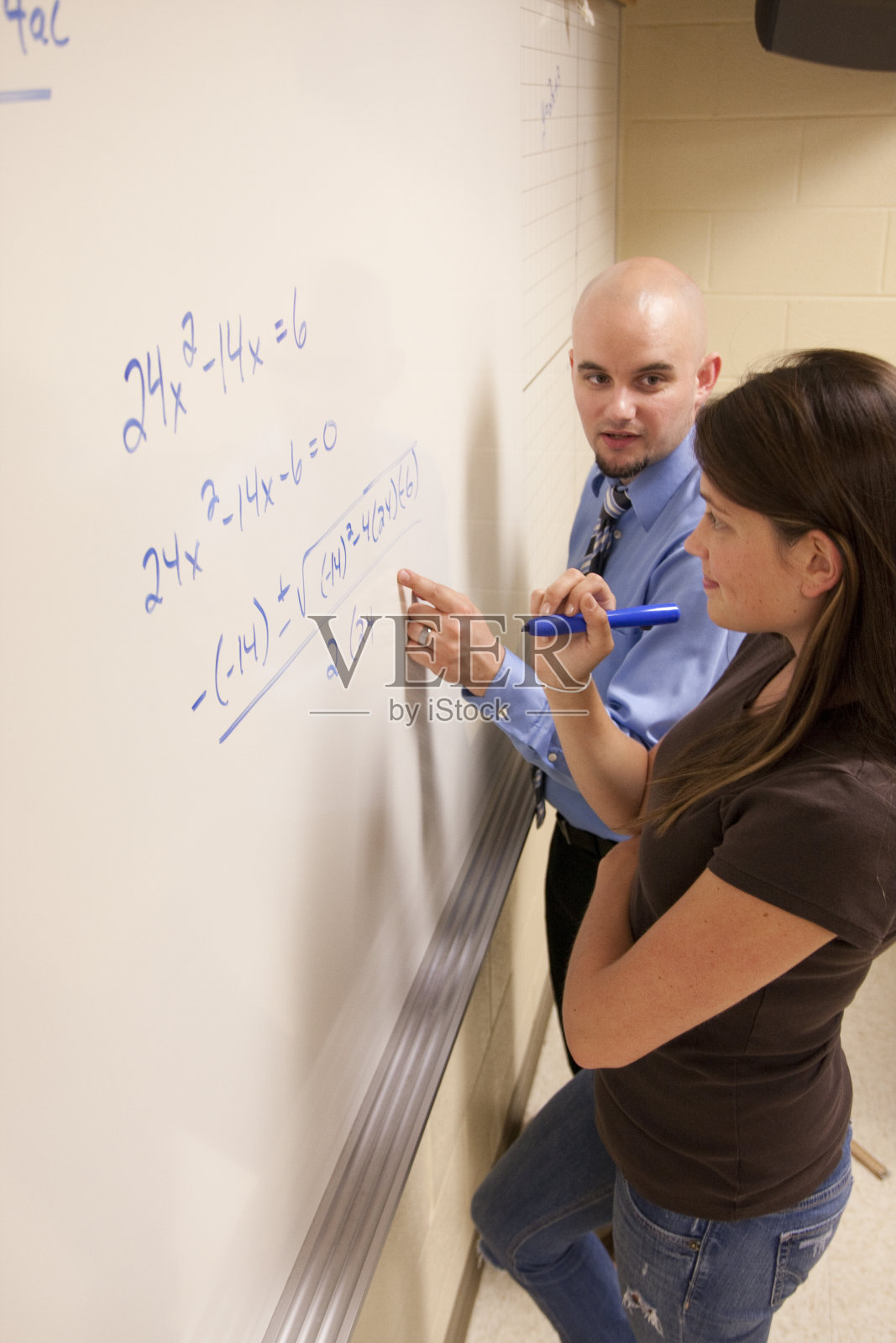 老师在白板上帮助学生解决数学问题。照片摄影图片