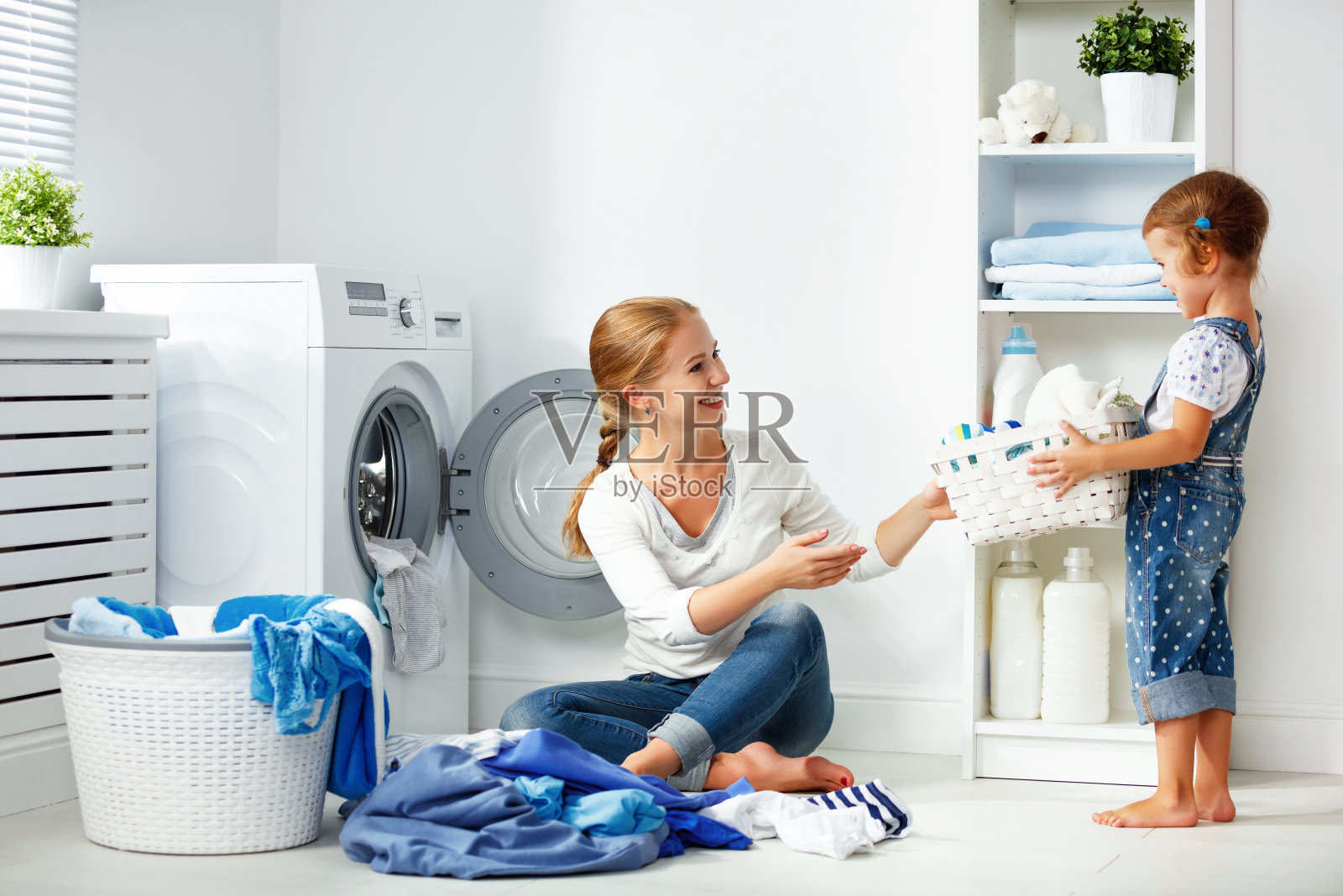 家庭母亲和孩子女孩在洗衣机附近的洗衣房照片摄影图片
