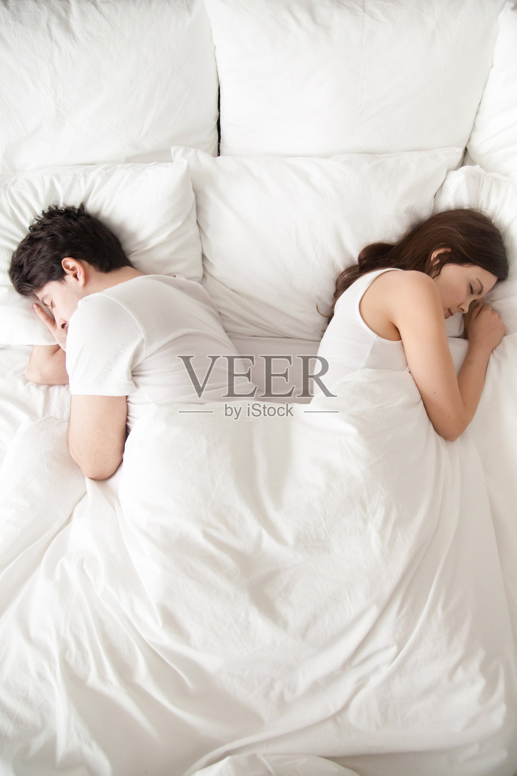 年轻夫妇分开睡在床上，背对背，垂直照片摄影图片