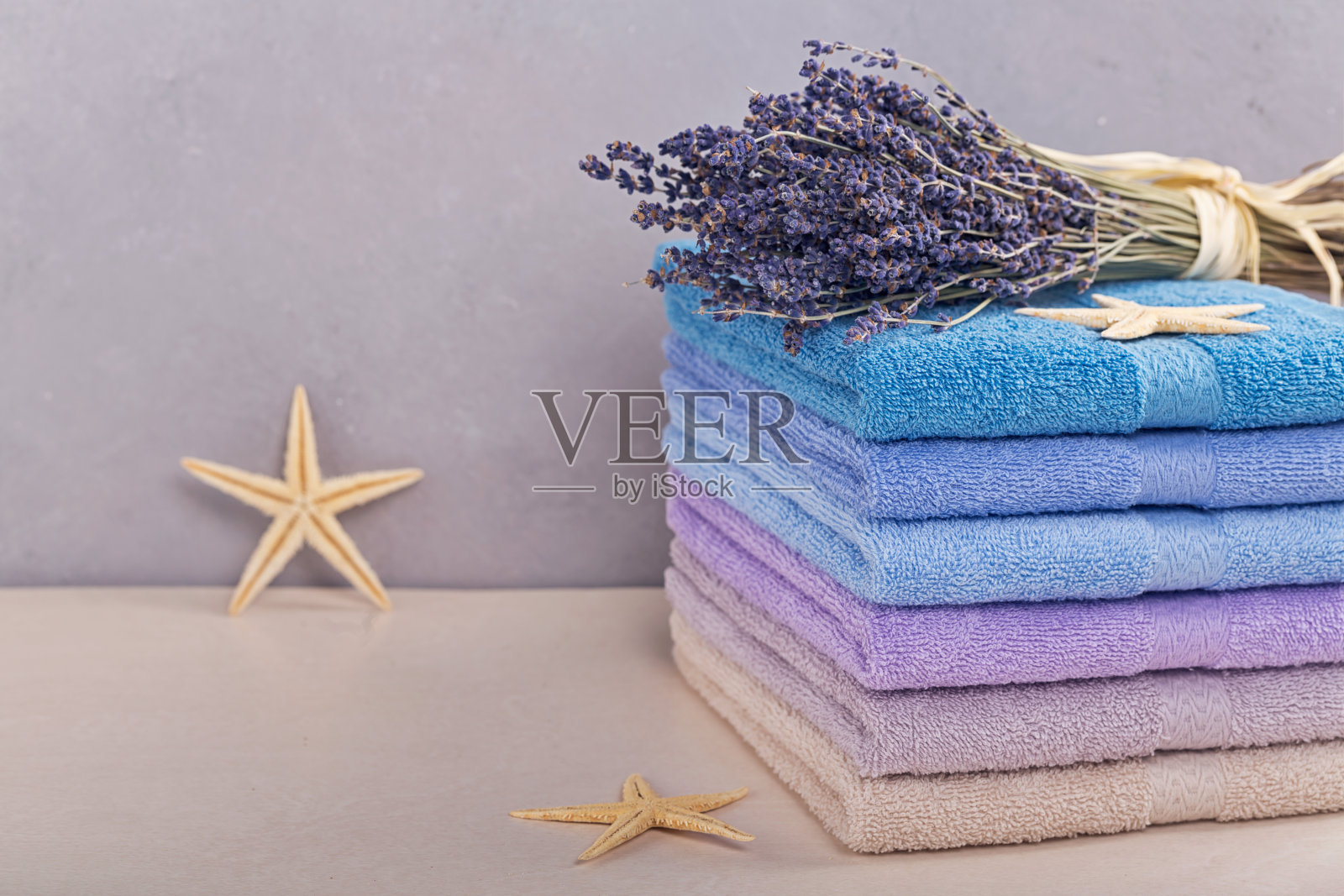 颜色鲜艳的浴巾堆叠在灯光背景上。色彩柔和的棉布毛巾。卫生，织物，水疗和纺织概念照片摄影图片