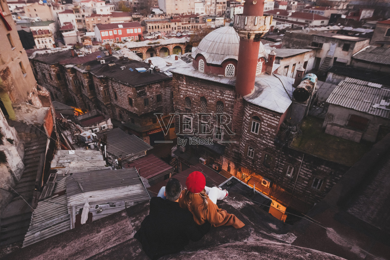 相爱的夫妇坐在屋顶上欣赏伊斯坦布尔的夜晚。休闲风格，秋风，红色贝雷帽和米色外套照片摄影图片