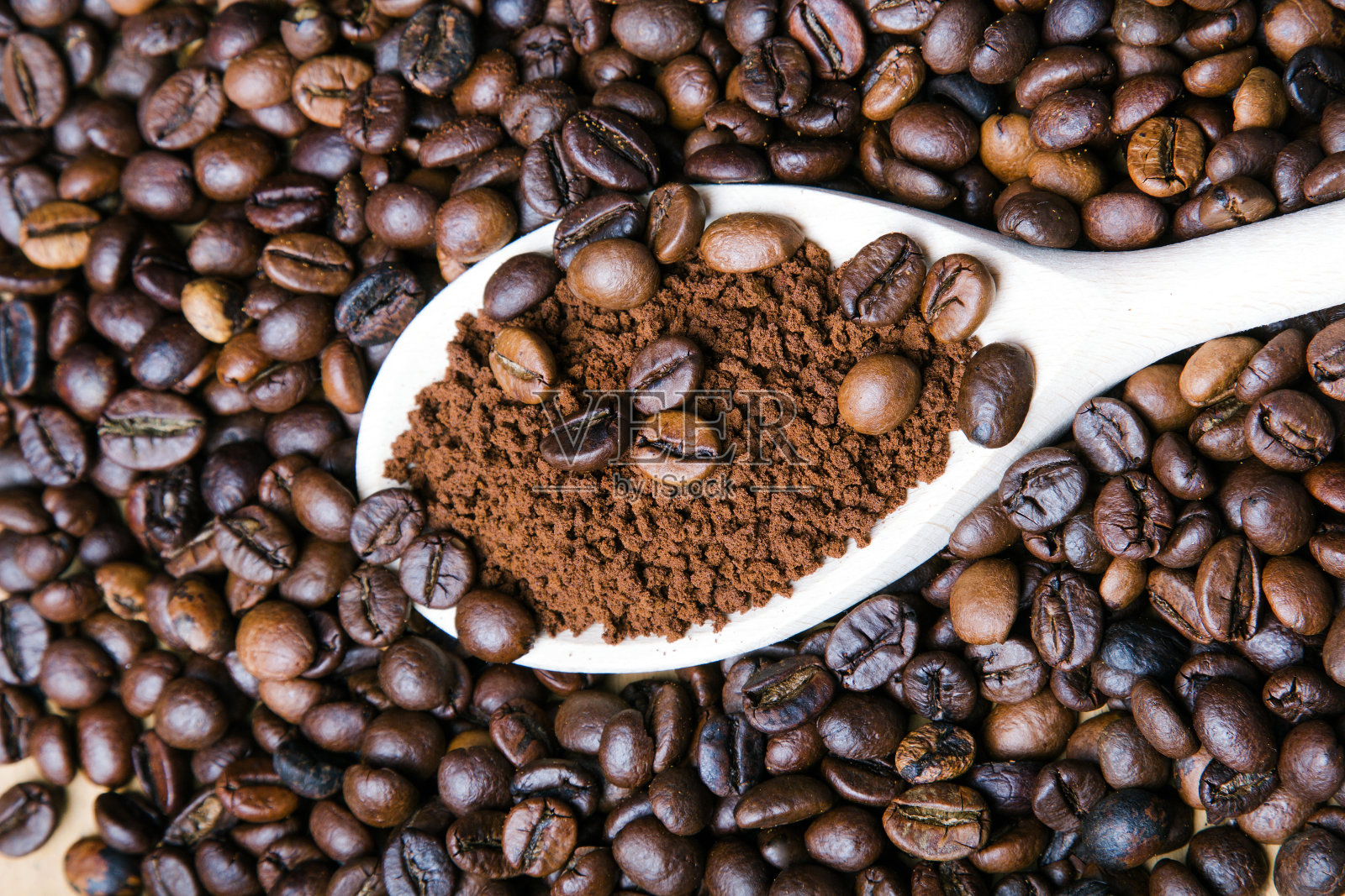在咖啡豆的背景下用勺子煮的速溶咖啡照片摄影图片