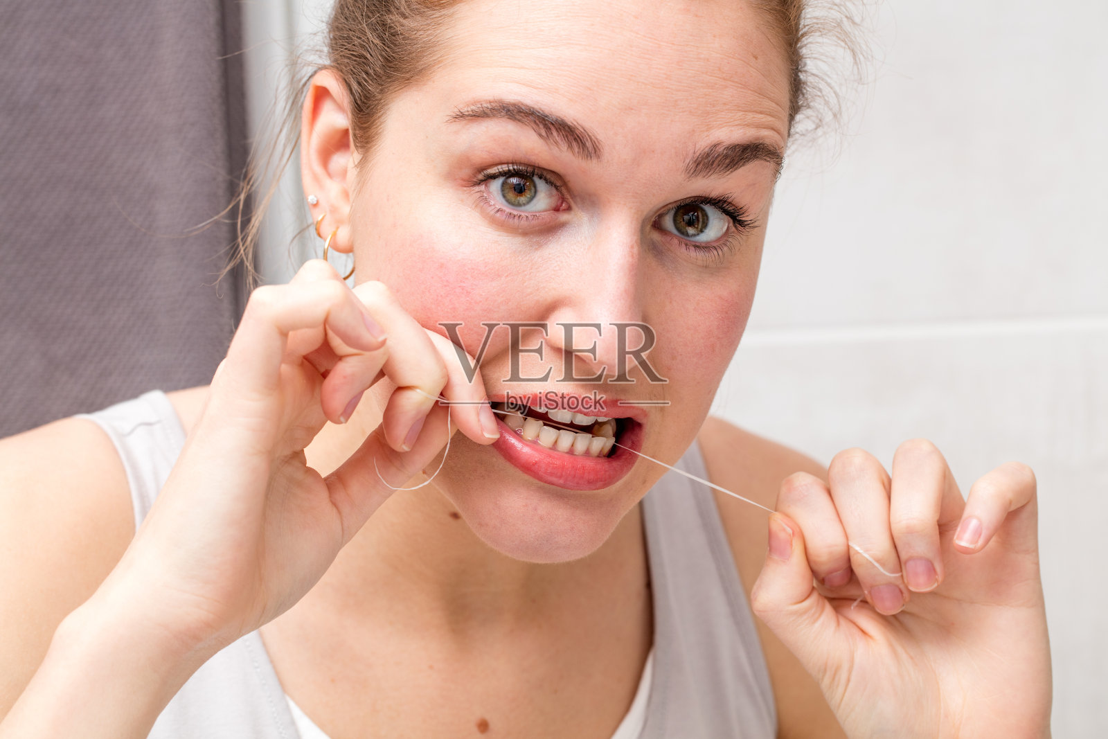 惊讶的年轻女子拿着牙线护理和清洁牙齿照片摄影图片