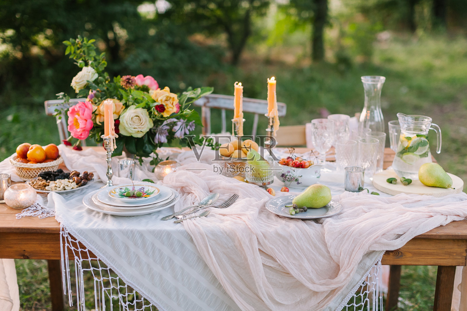 婚礼，装饰，庆典，花卉设计，假日概念-浪漫的餐桌设置白色桌布，盘子，水晶酒杯，美丽的玫瑰和牡丹花束和蜡烛照片摄影图片